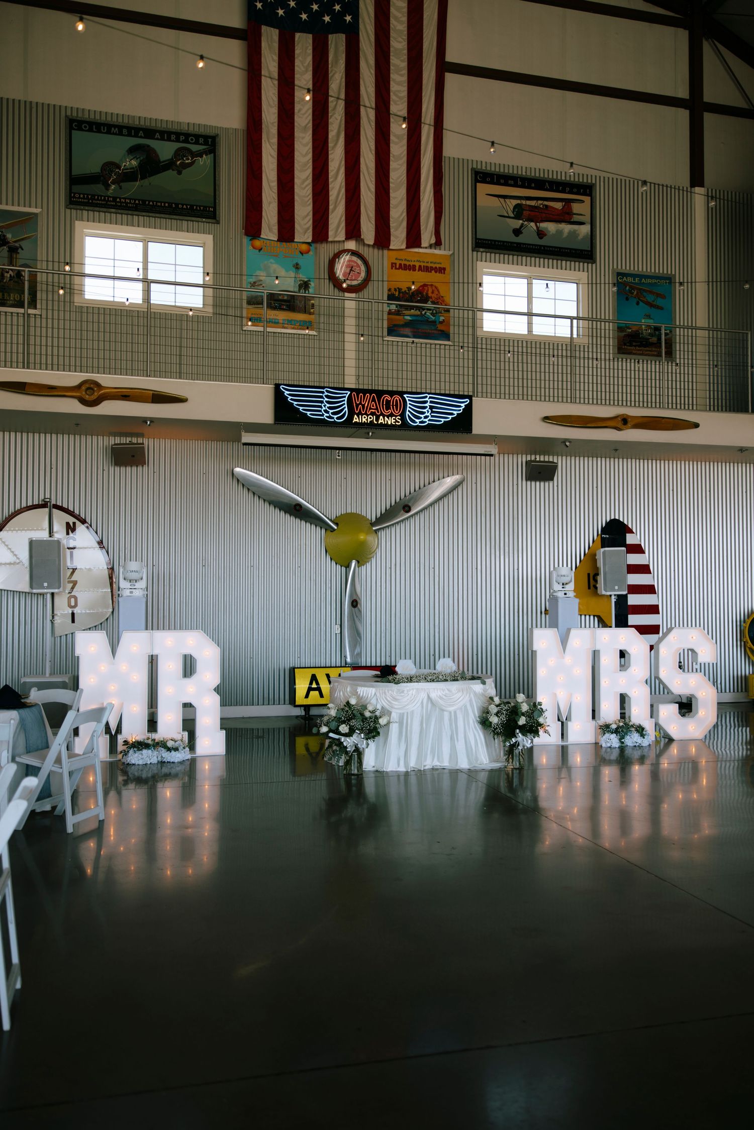Large white 'MR & MRS' letters displayed in an event venue with American flags on the walls.