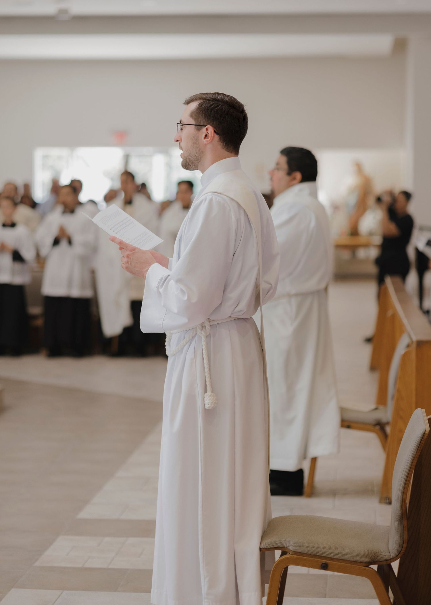 People in white robes stand in prayer during a church service.
