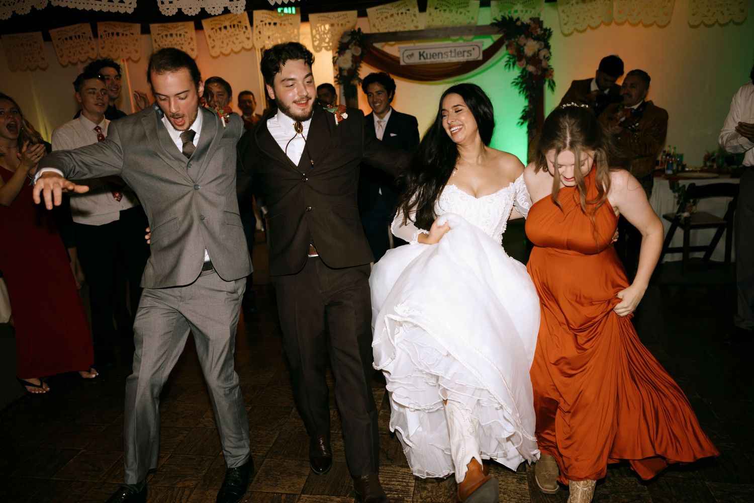 Wedding reception dance floor with guests in formal attire enjoying the celebration.