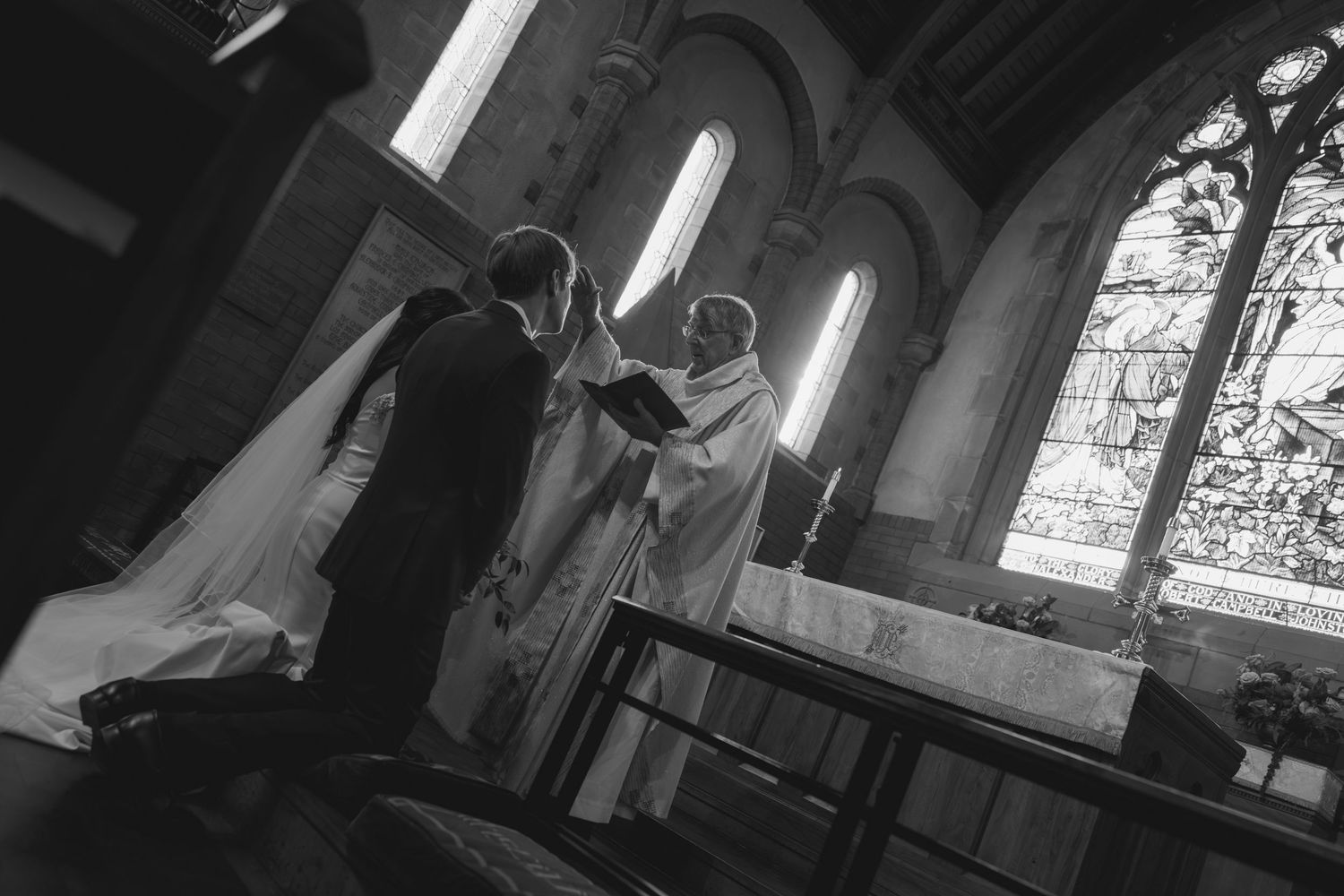 Church sanctuary with dramatic lighting from windows during wedding ceremony.