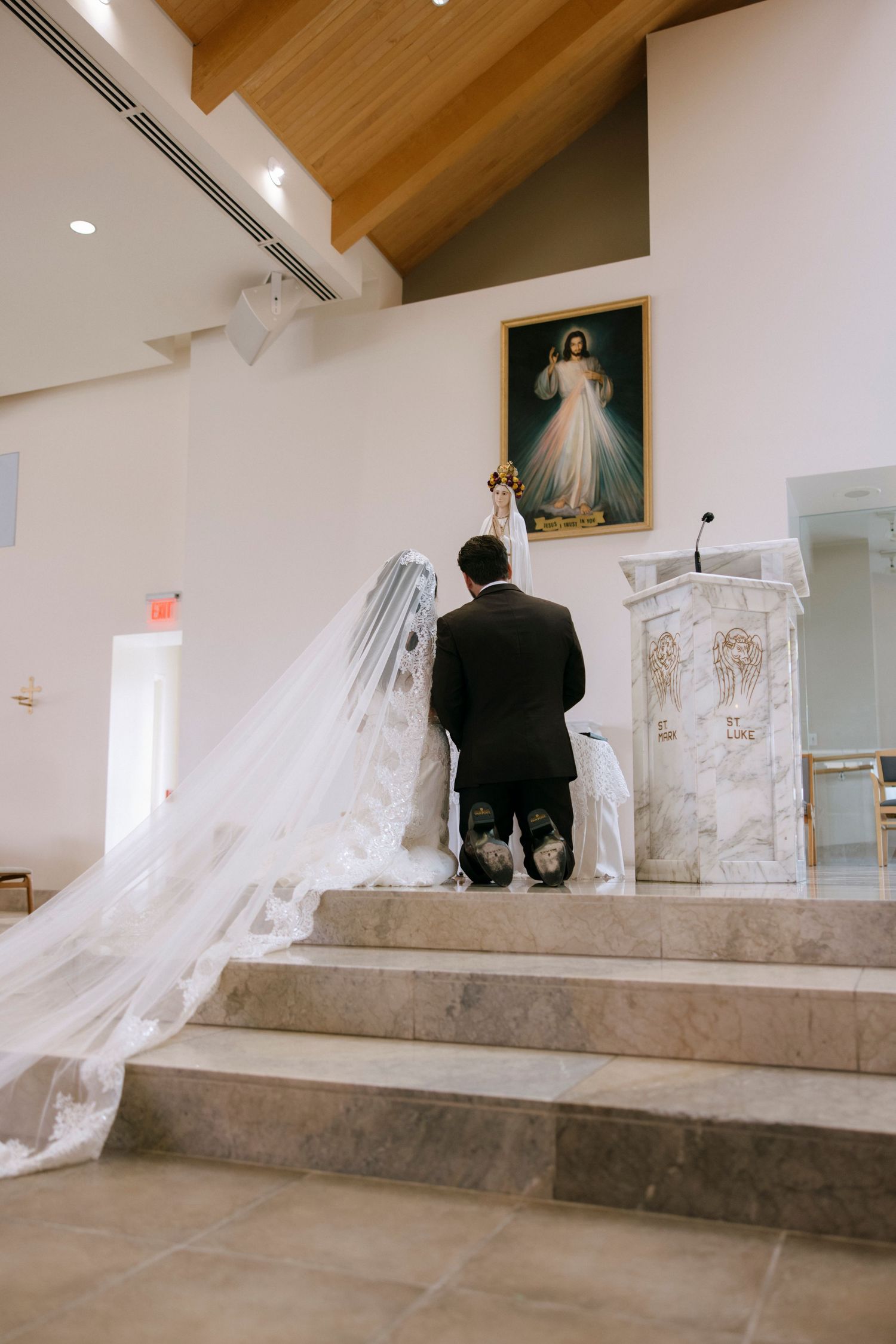 Wedding couple kneeling at church altar steps during their ceremony.