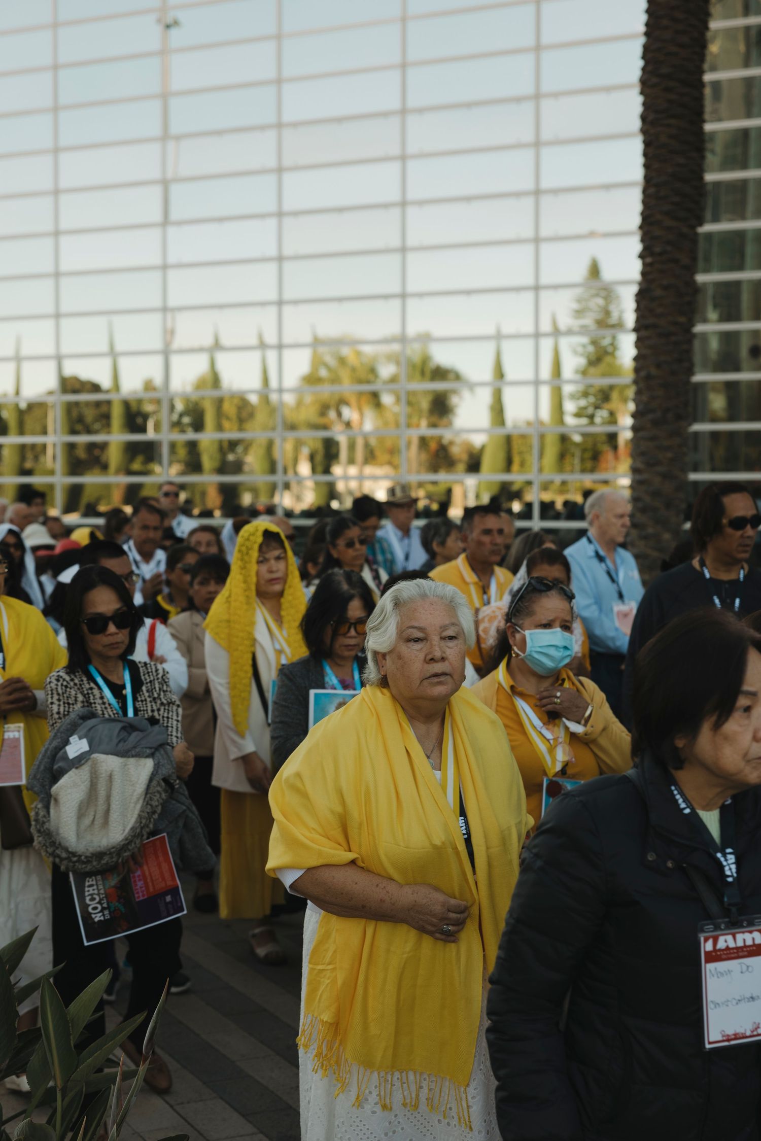 Diverse crowd gathered outside modern building for religious event at sunset.