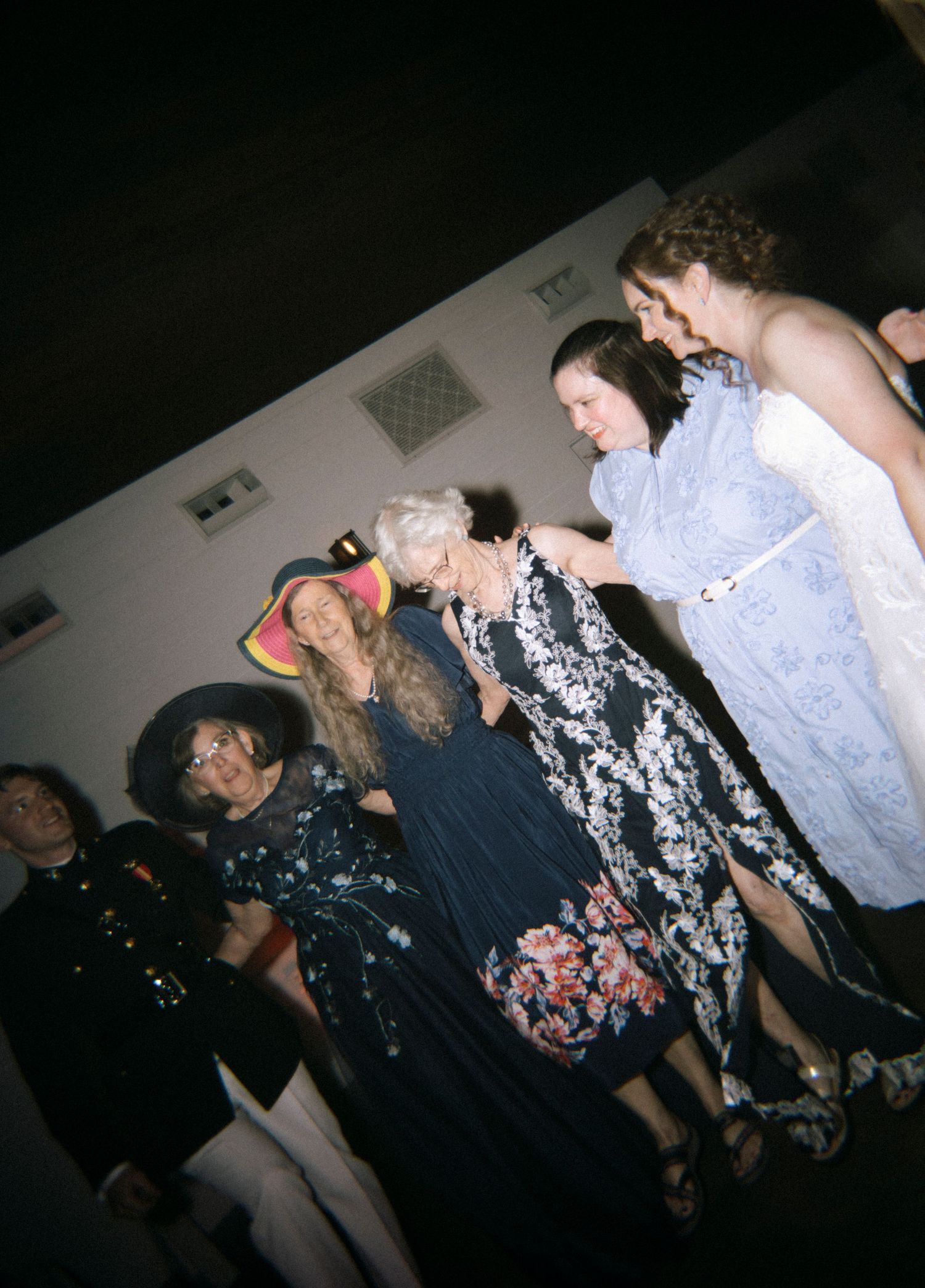 Group of women in elegant dresses gathered together at a formal event or gallery opening.