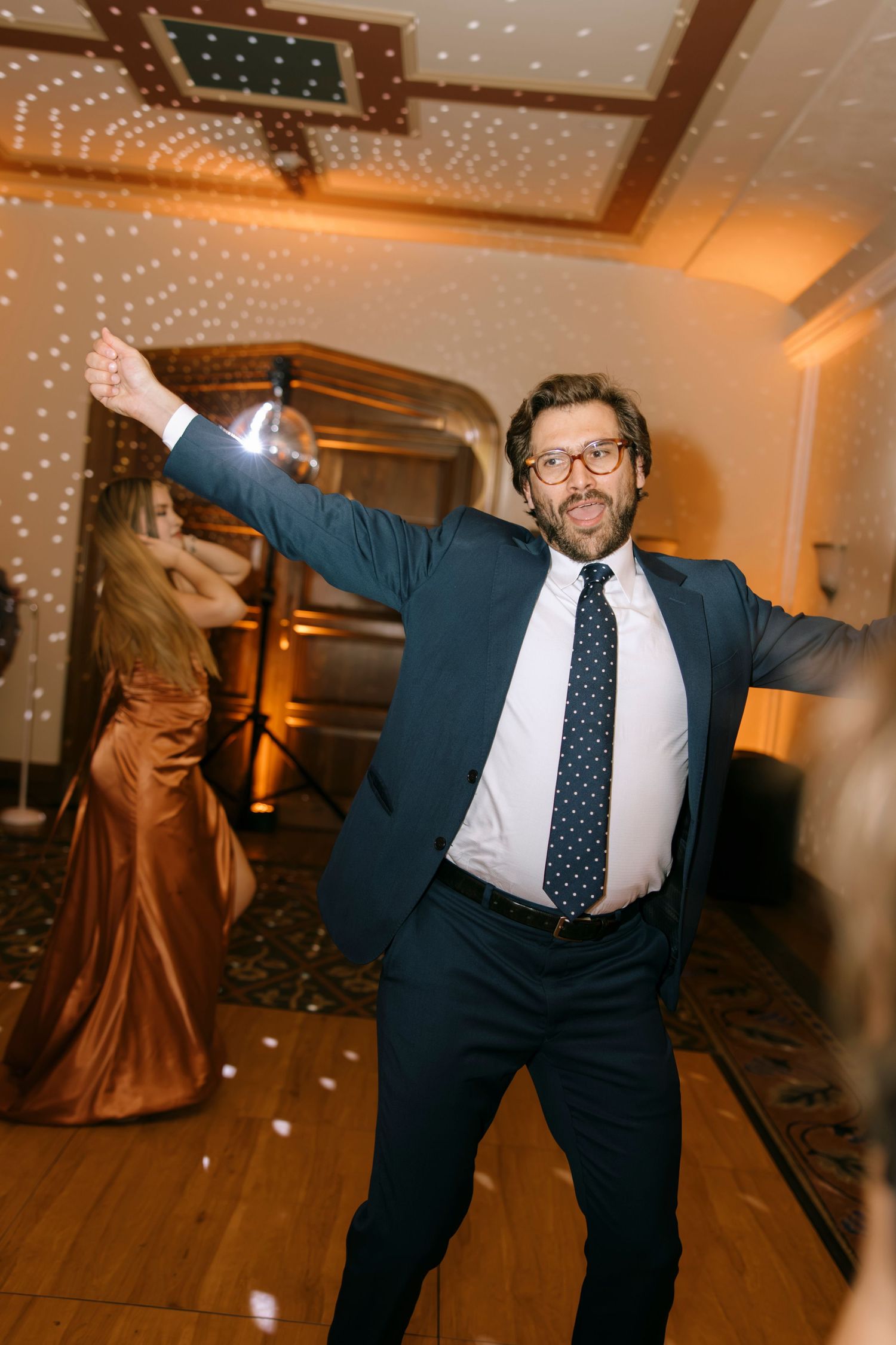 Guest dancing enthusiastically on illuminated dance floor at wedding reception.