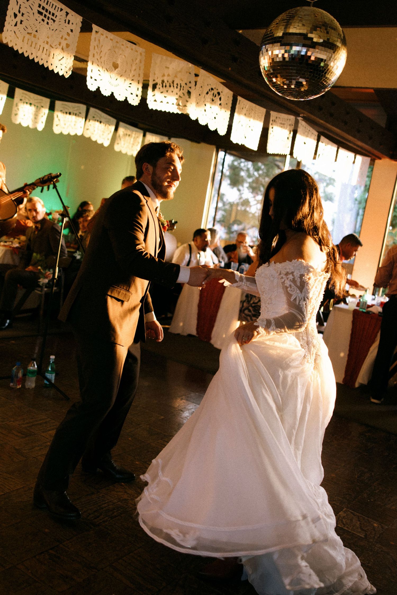 Wedding reception dance floor with couples dancing under ambient lighting and disco ball.