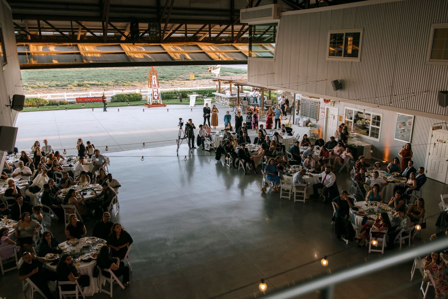 Wide view of wedding reception venue with guests seated at round tables.