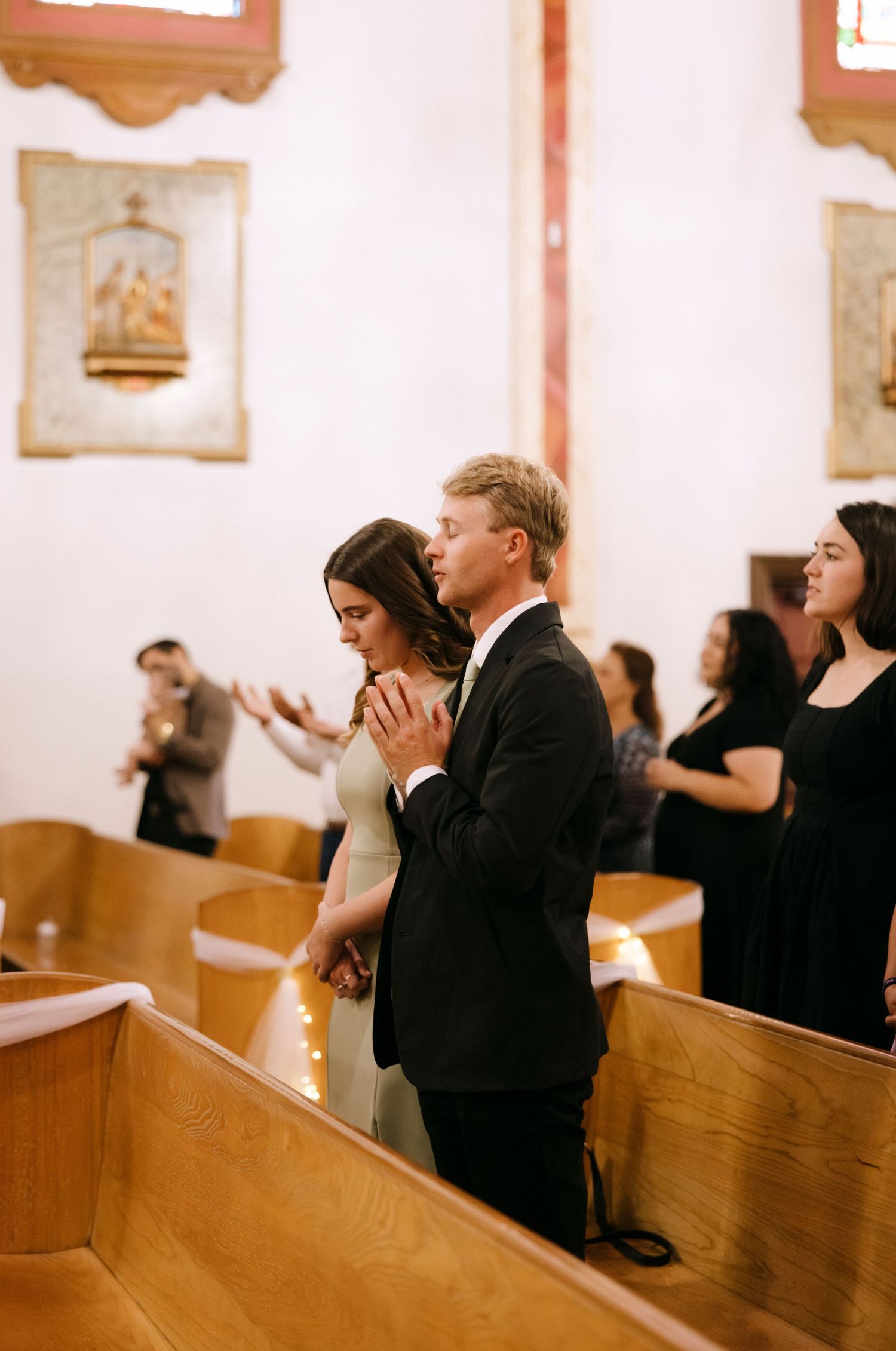 People sitting in wooden church pews during a religious service.