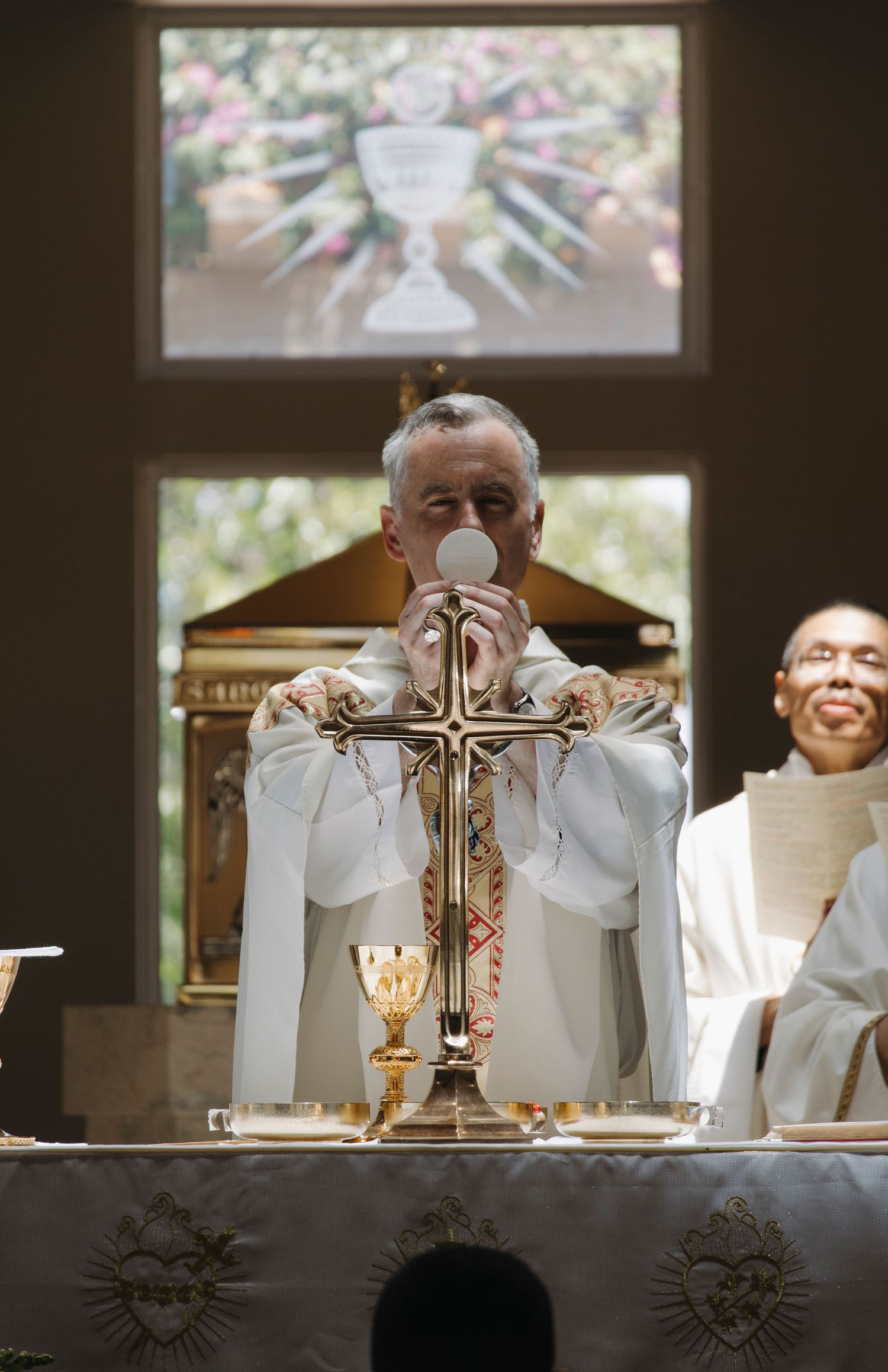 Priest performing consecration with chalice during Catholic mass.
