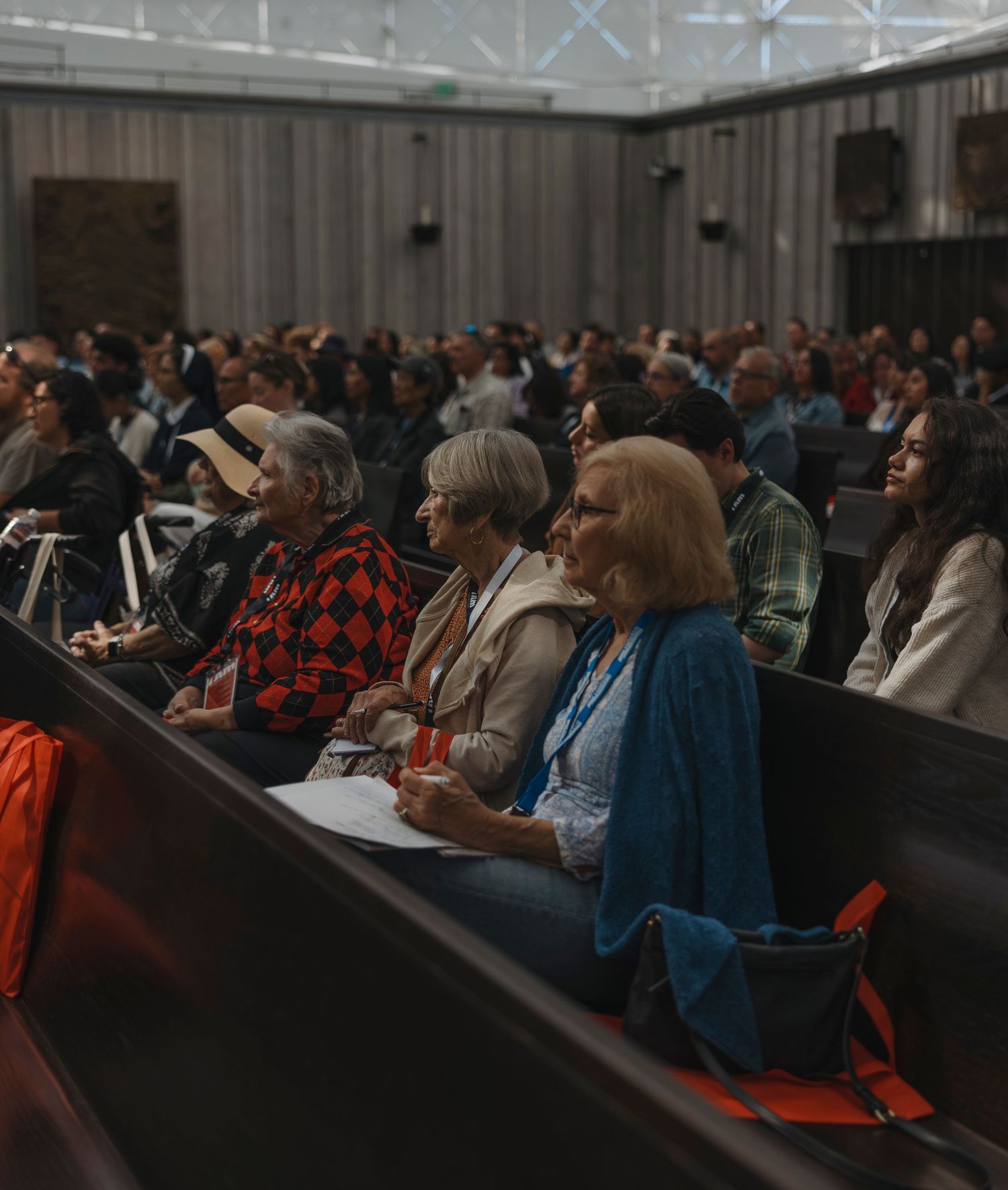 Audience members sit attentively in church pews during a presentation or service.