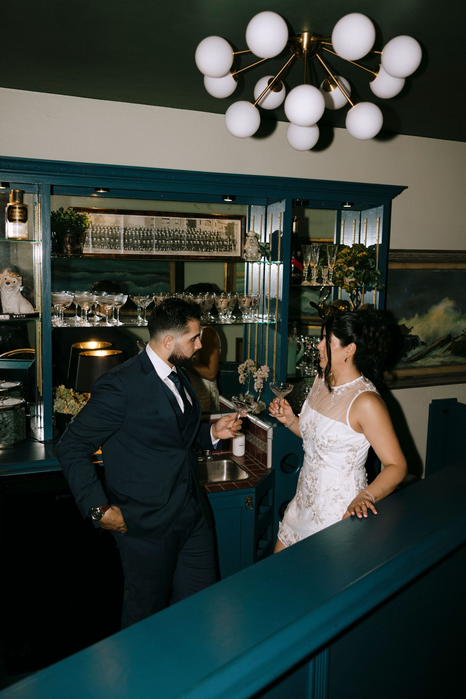 Newlyweds share playful interactions at an indoor venue with globe pendant lights.