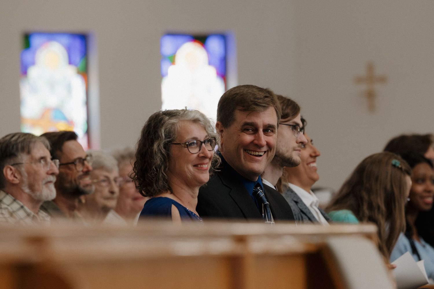 Church congregation gathered for worship with stained glass windows visible.