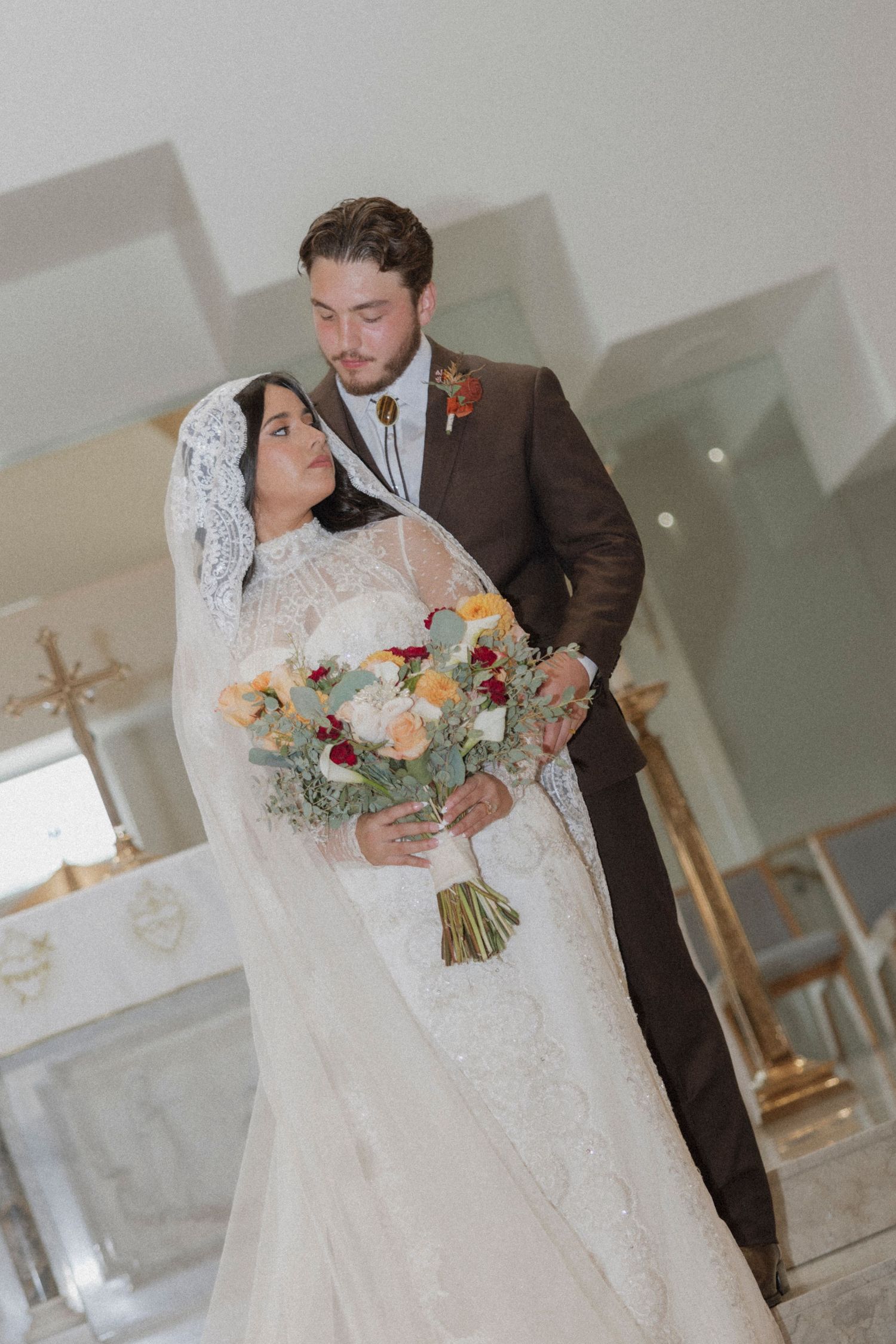 Wedding couple with colorful bouquet in elegant church setting.