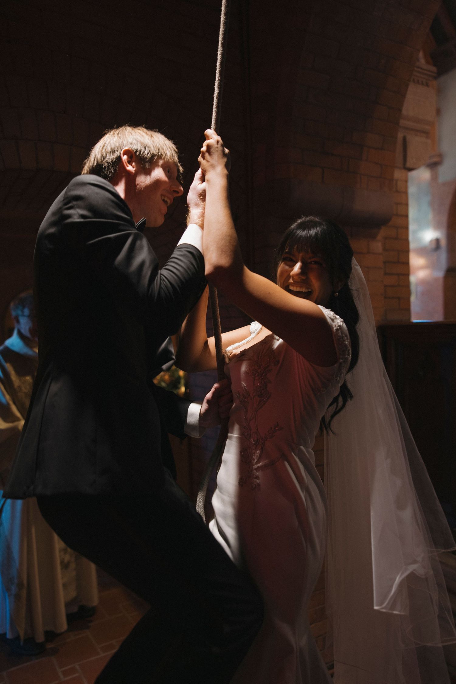 Wedding couple dances together in dimly lit brick interior.