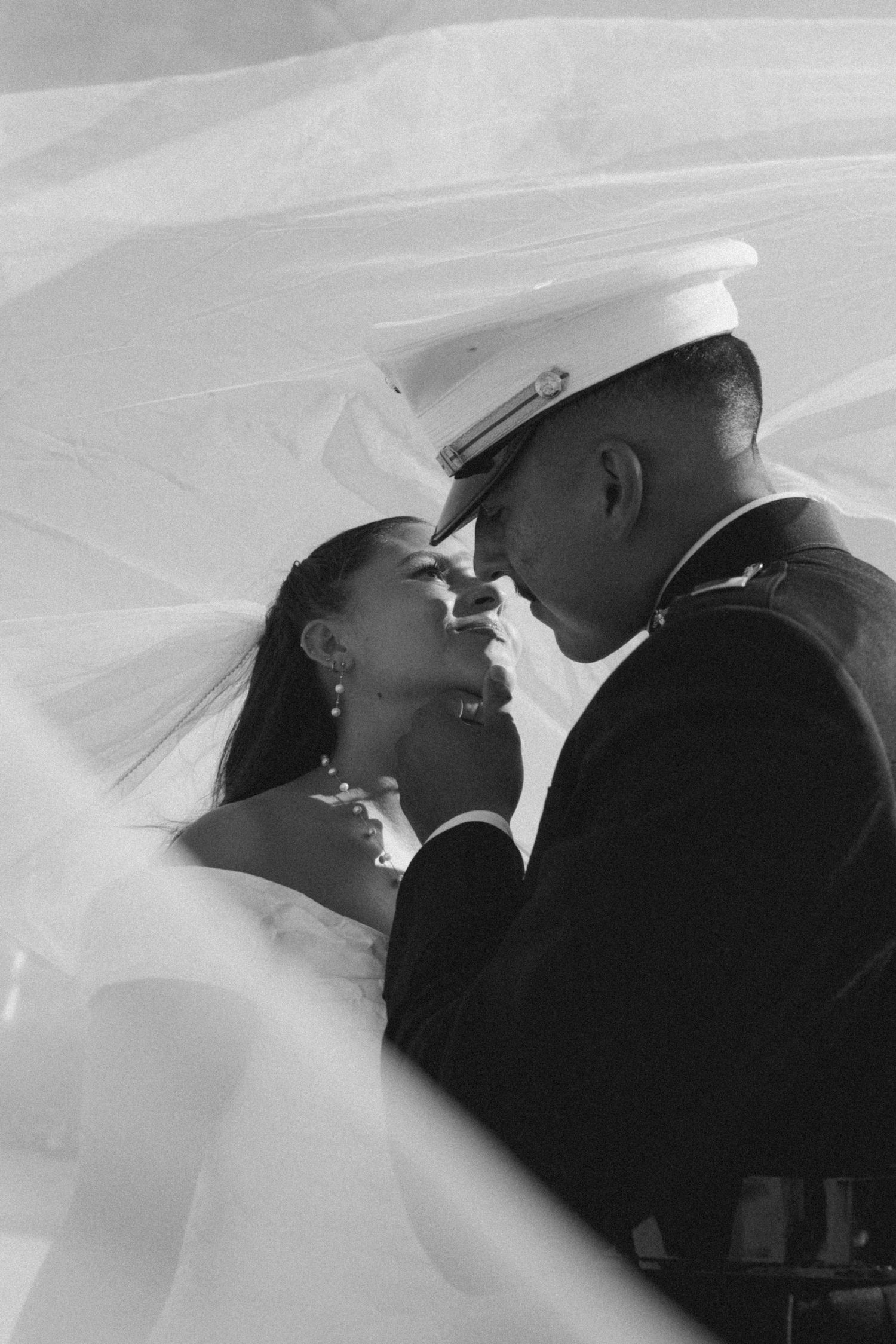 Silhouetted wedding couple sharing romantic moments under a flowing veil.