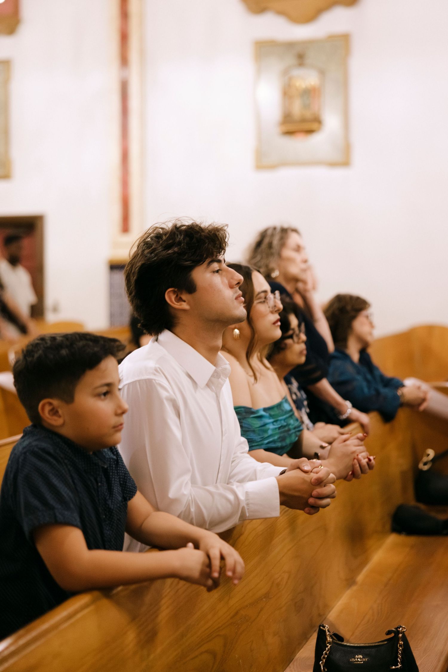 Congregation members seated in wooden pews looking upward during a church service.