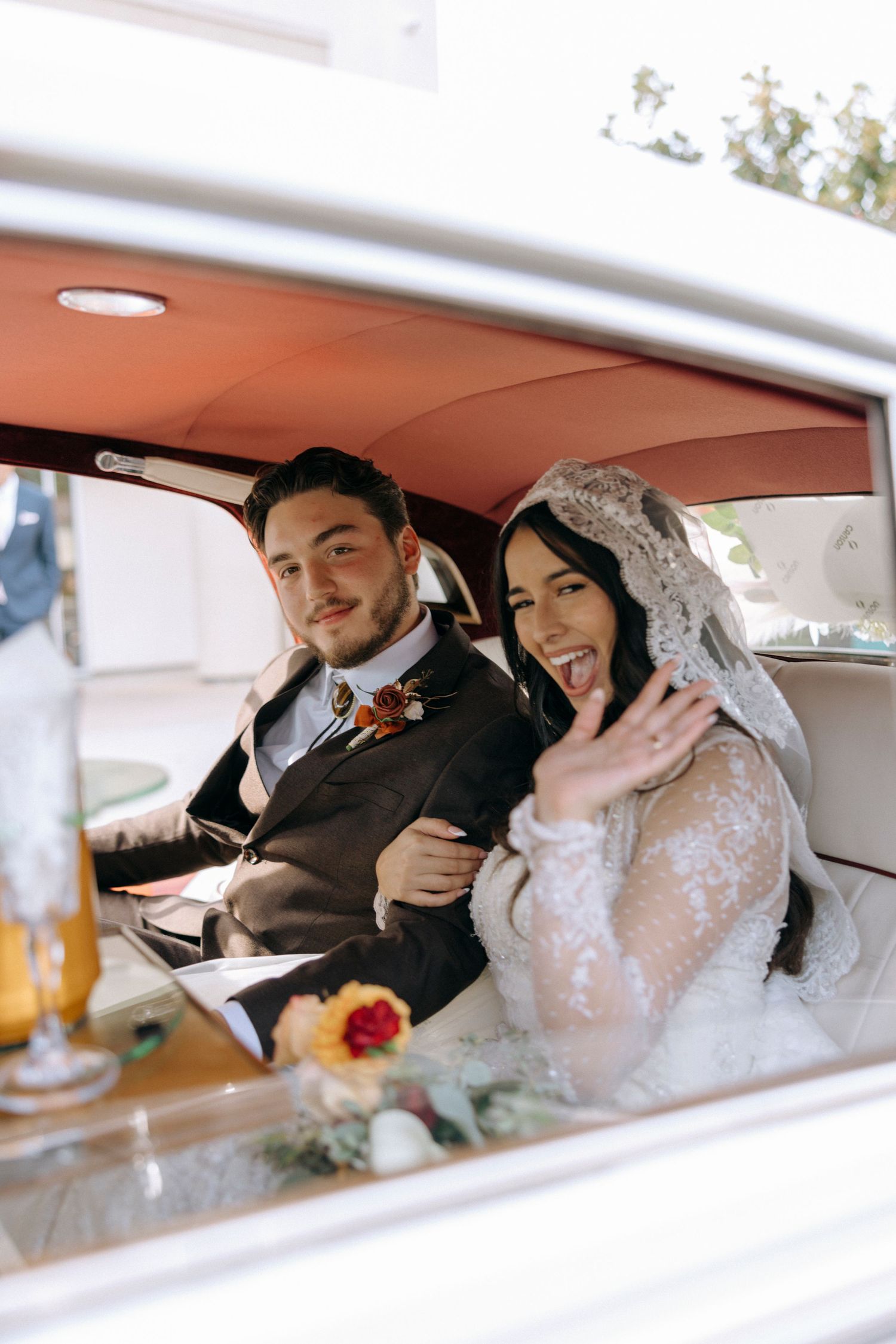 Newlyweds share intimate moments in a vintage car after their wedding ceremony.