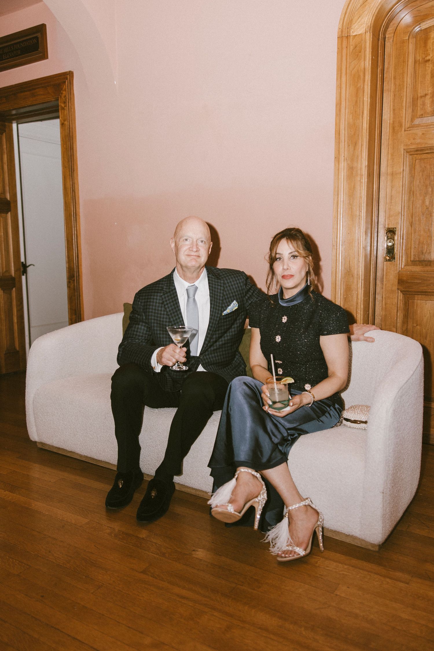 Wedding guests relaxing on white couches during an elegant indoor reception.