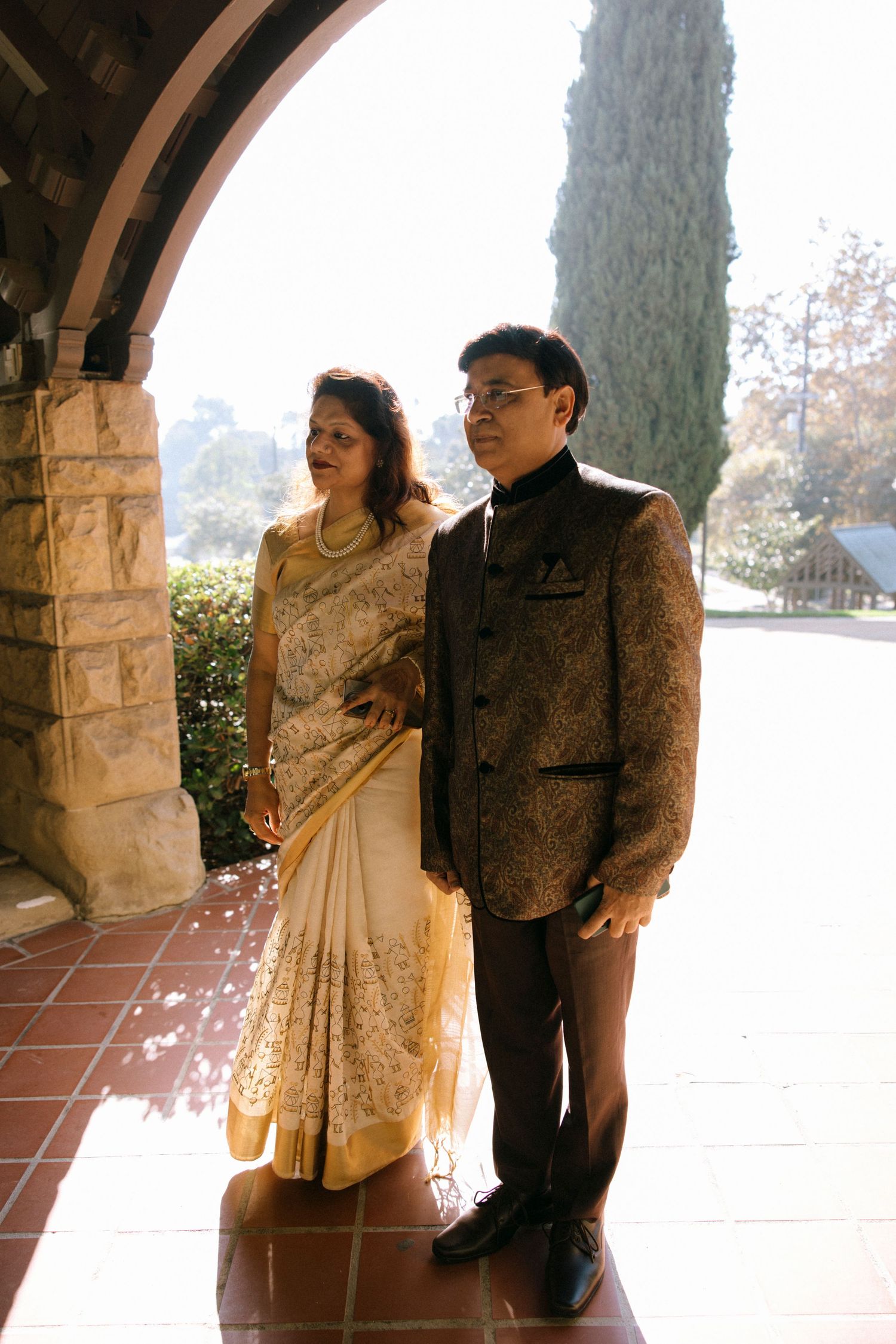 Wedding couple poses under stone archway during formal portrait session.