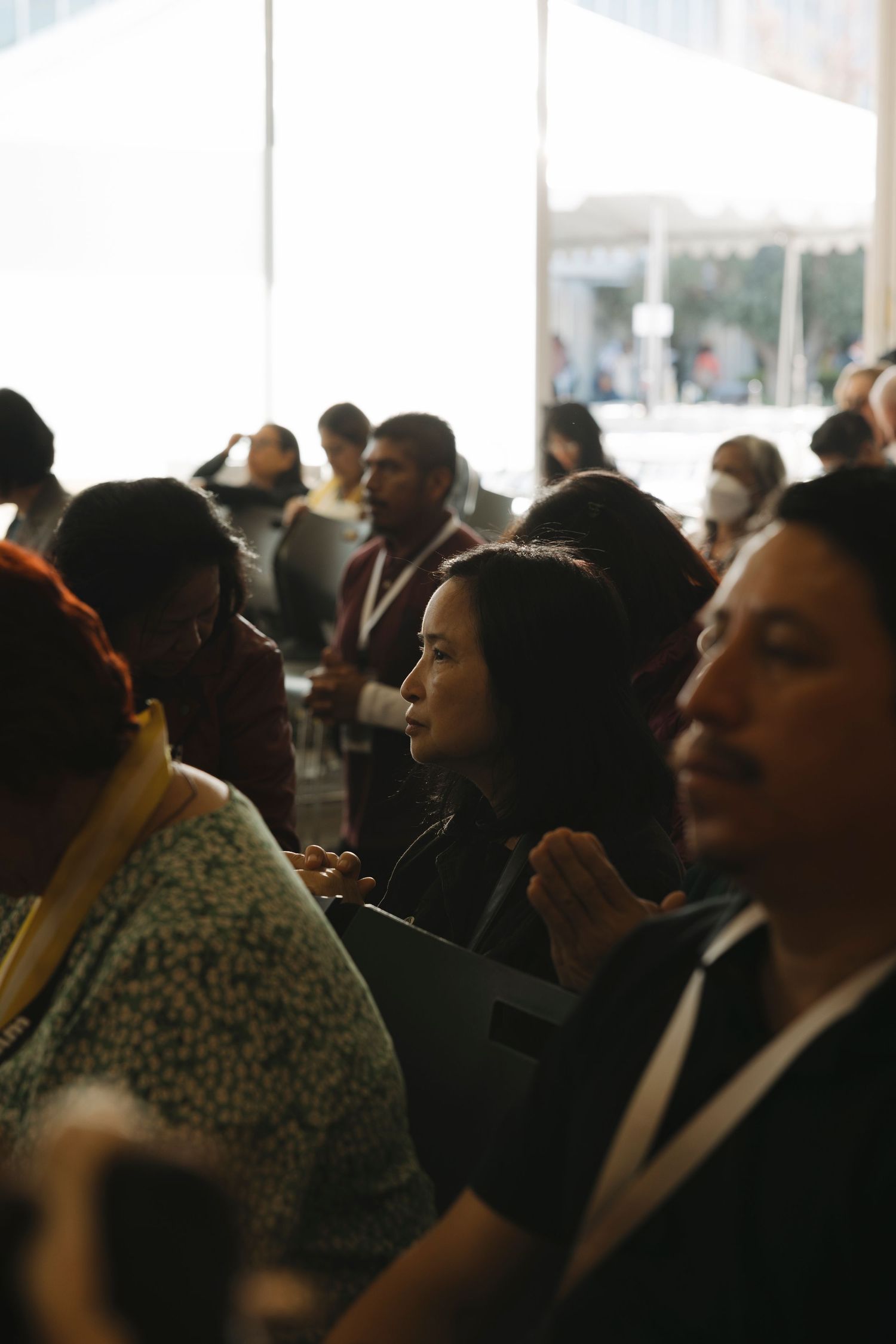 Crowd of attendees gathered indoors under bright lighting for a religious service.