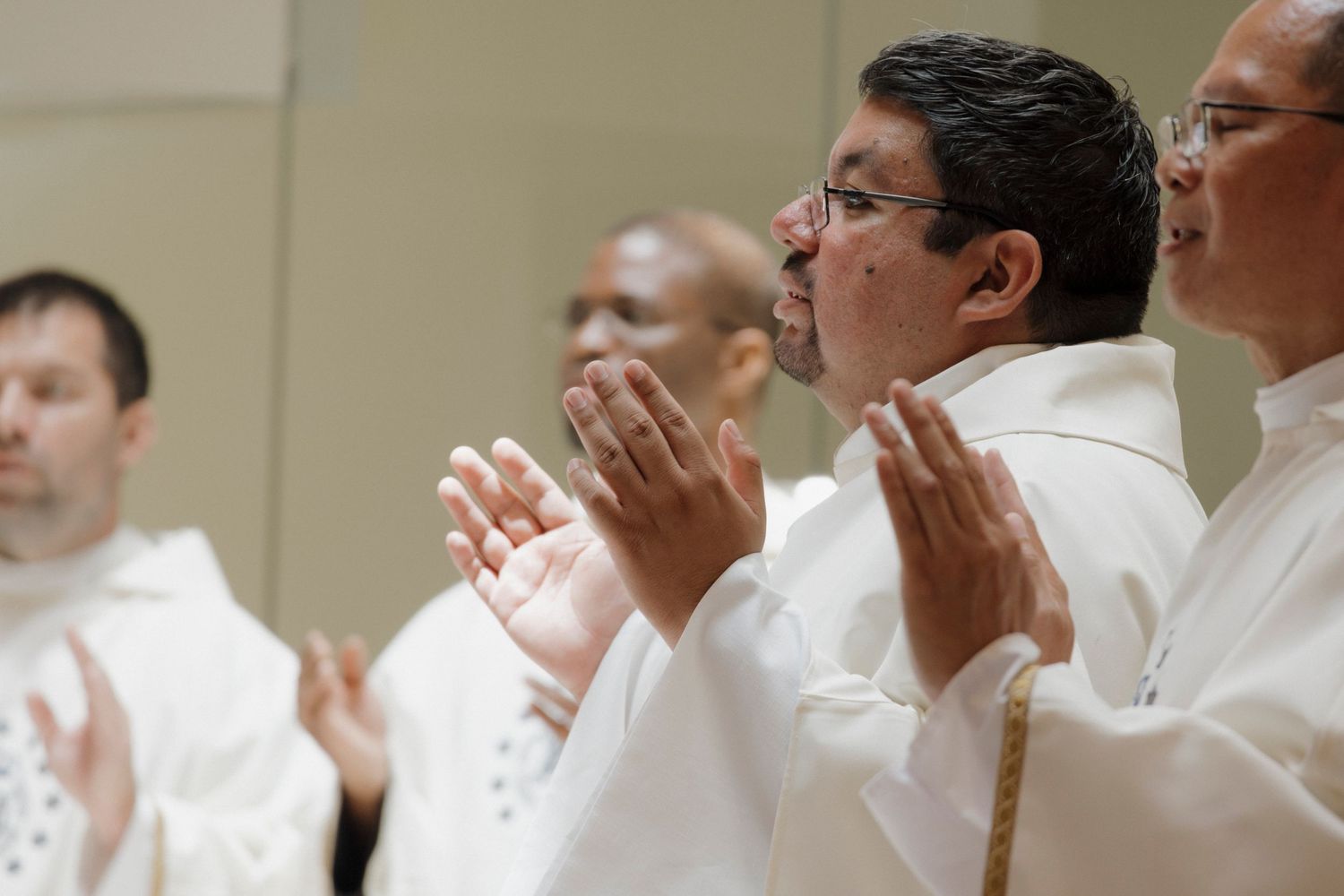 Clergy members gathered in prayer wearing traditional white vestments.