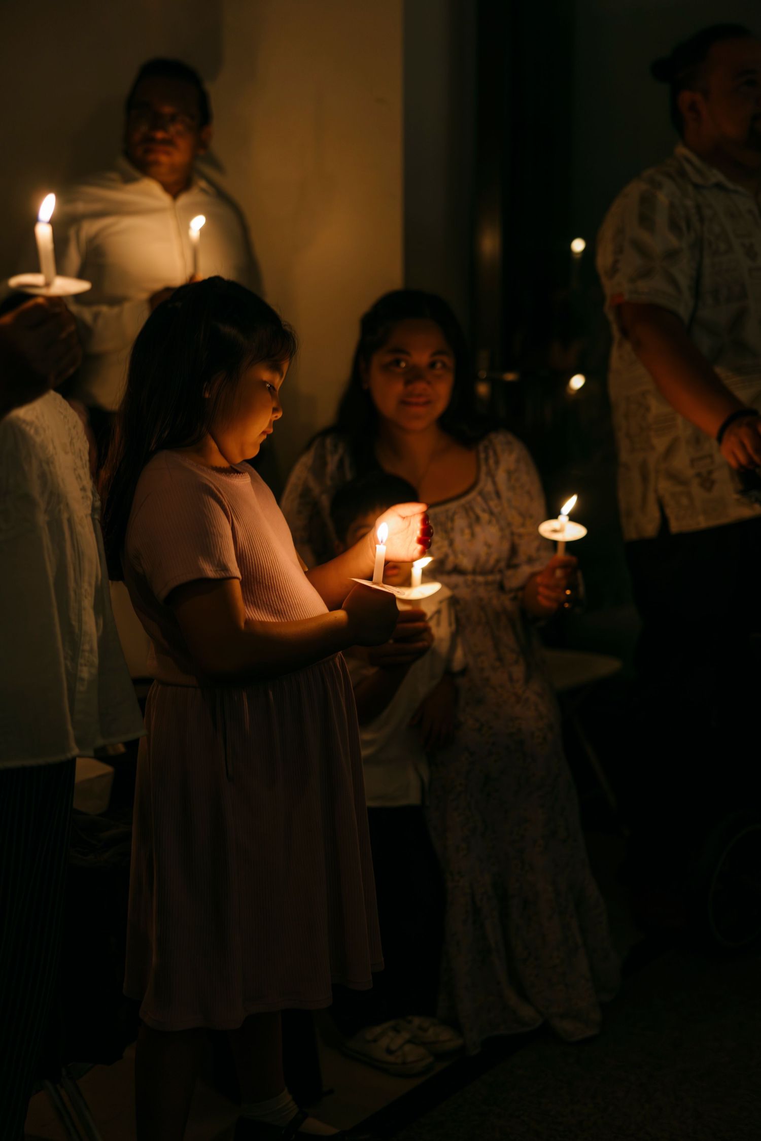 Young girl and woman holding candles together during Catholic Easter Vigil church service.