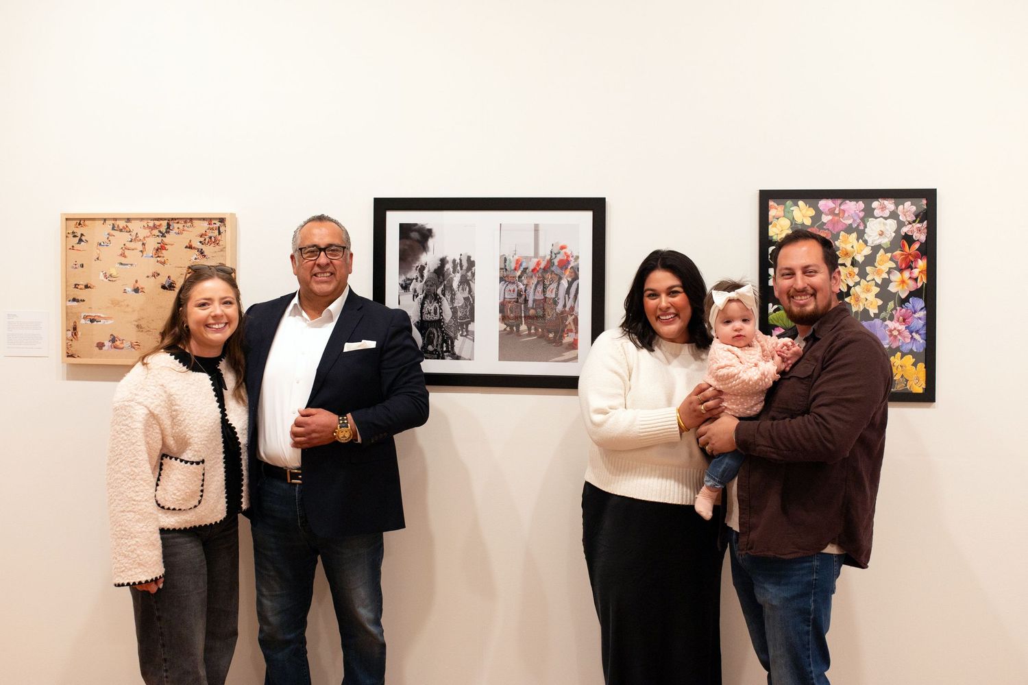 Art gallery opening with attendees viewing photographs displayed on beige walls.
