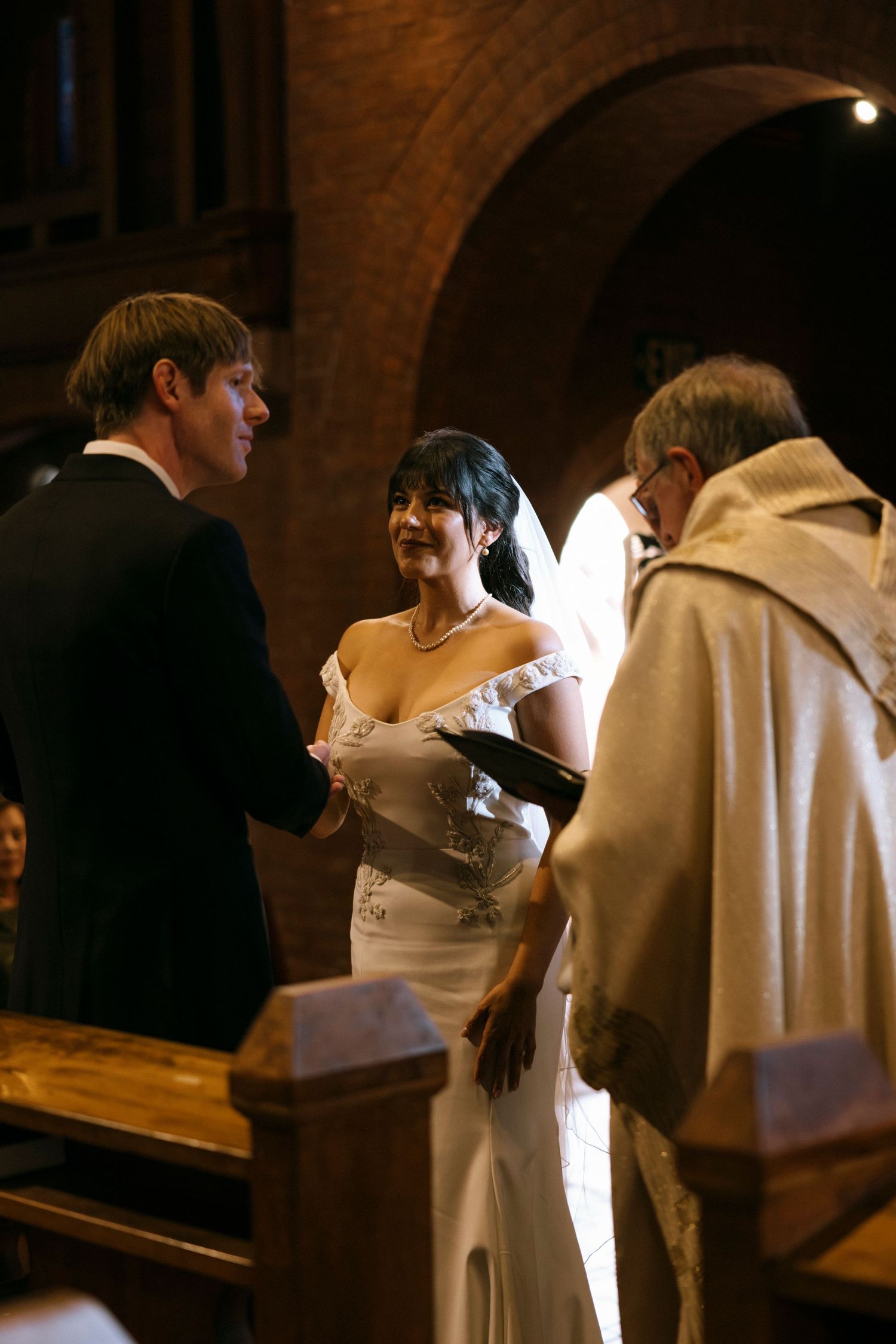Wedding ceremony in progress with couple and officiant standing at church altar.