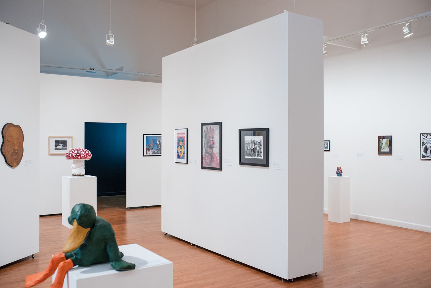 Modern art gallery interior with white walls and suspended lighting fixtures.