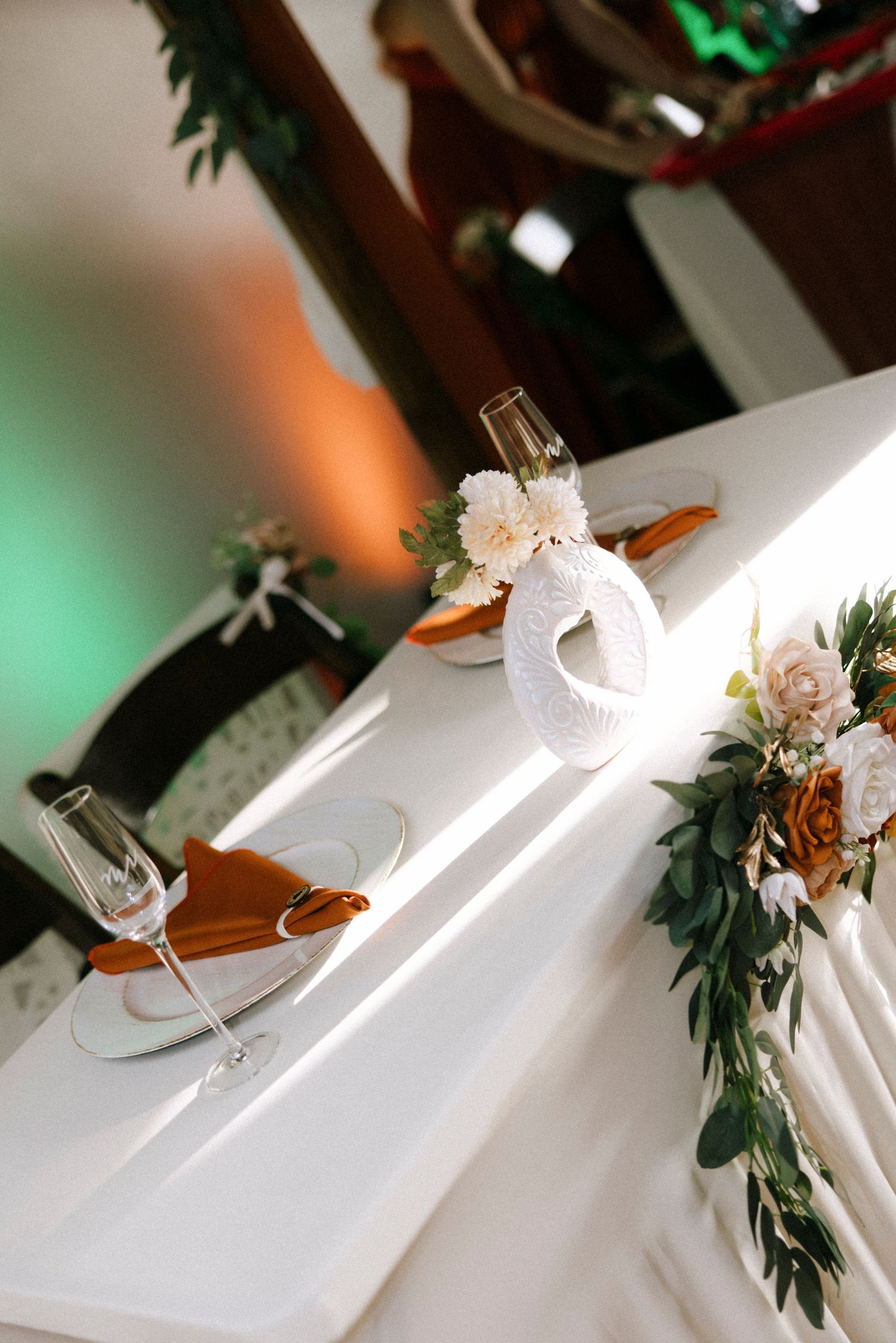 Wedding reception table settings with white linens and floral centerpieces in natural light.