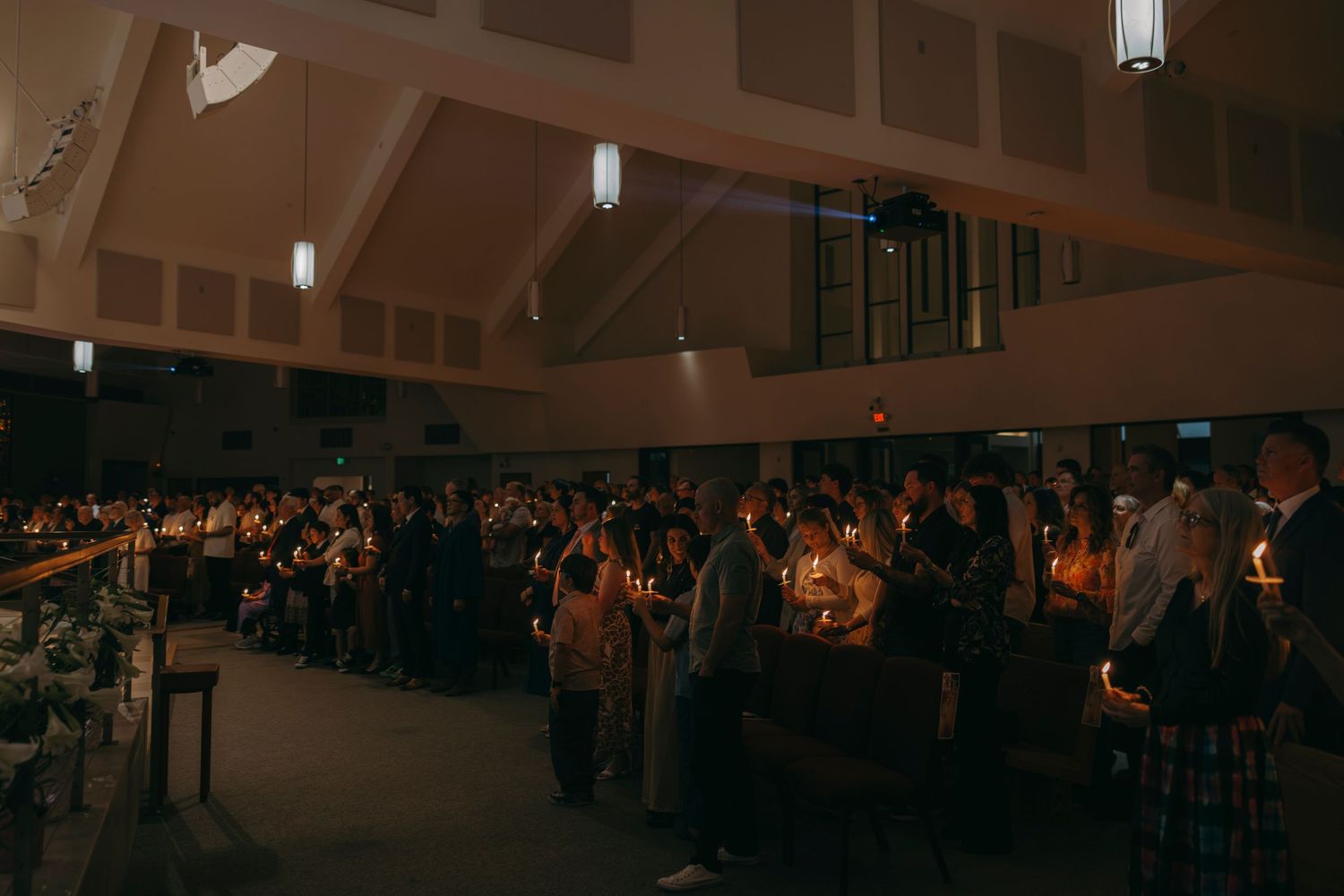 Congregation holding candles during a candlelight church service in a dimly lit sanctuary.