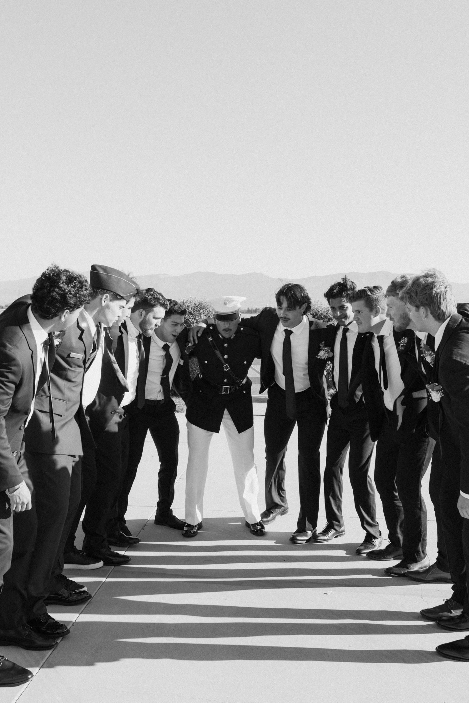 Black and white silhouette of wedding party creating dramatic line formation outdoors.