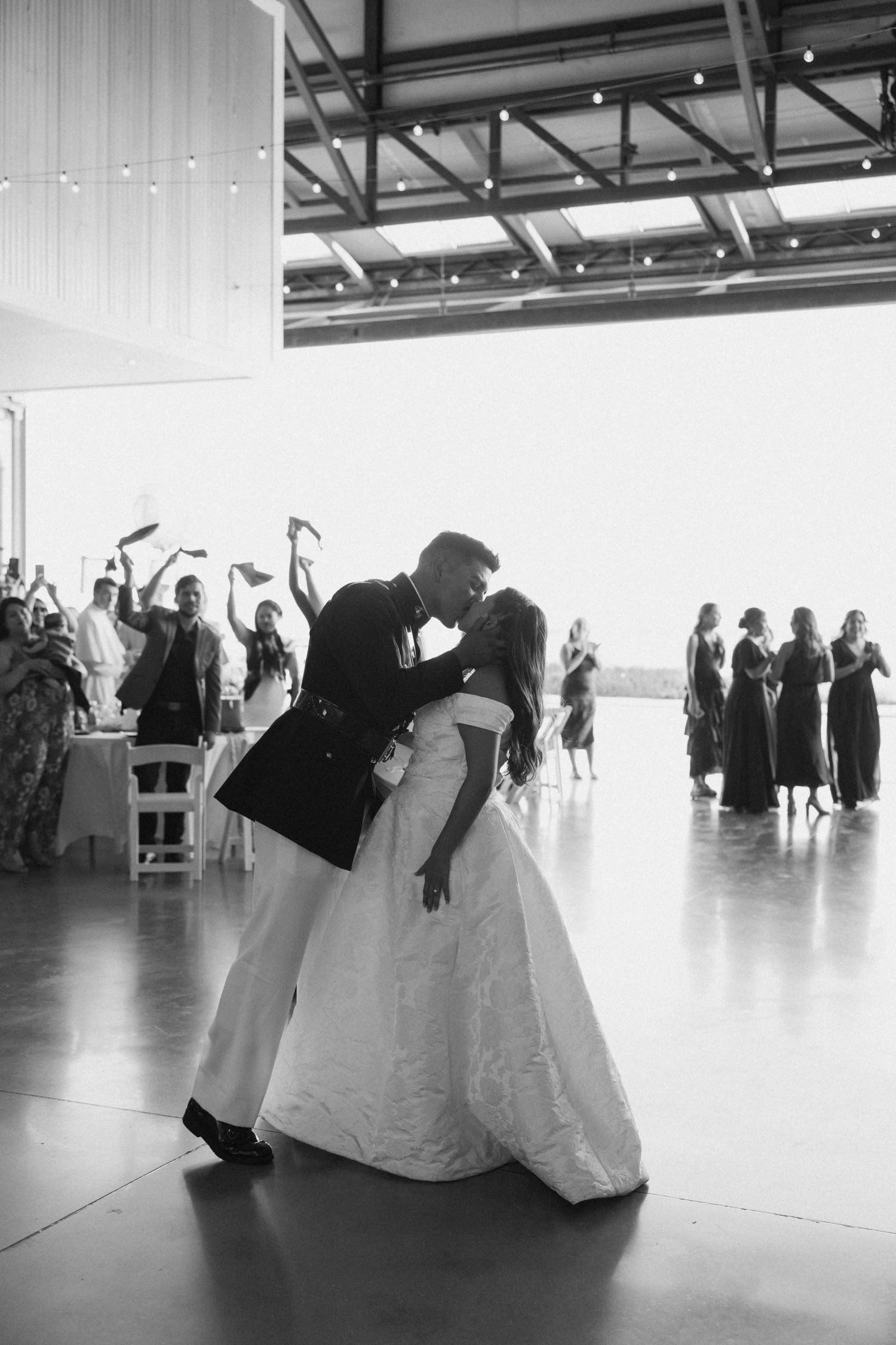 Black and white photo of wedding party dancing in formation on a polished floor.