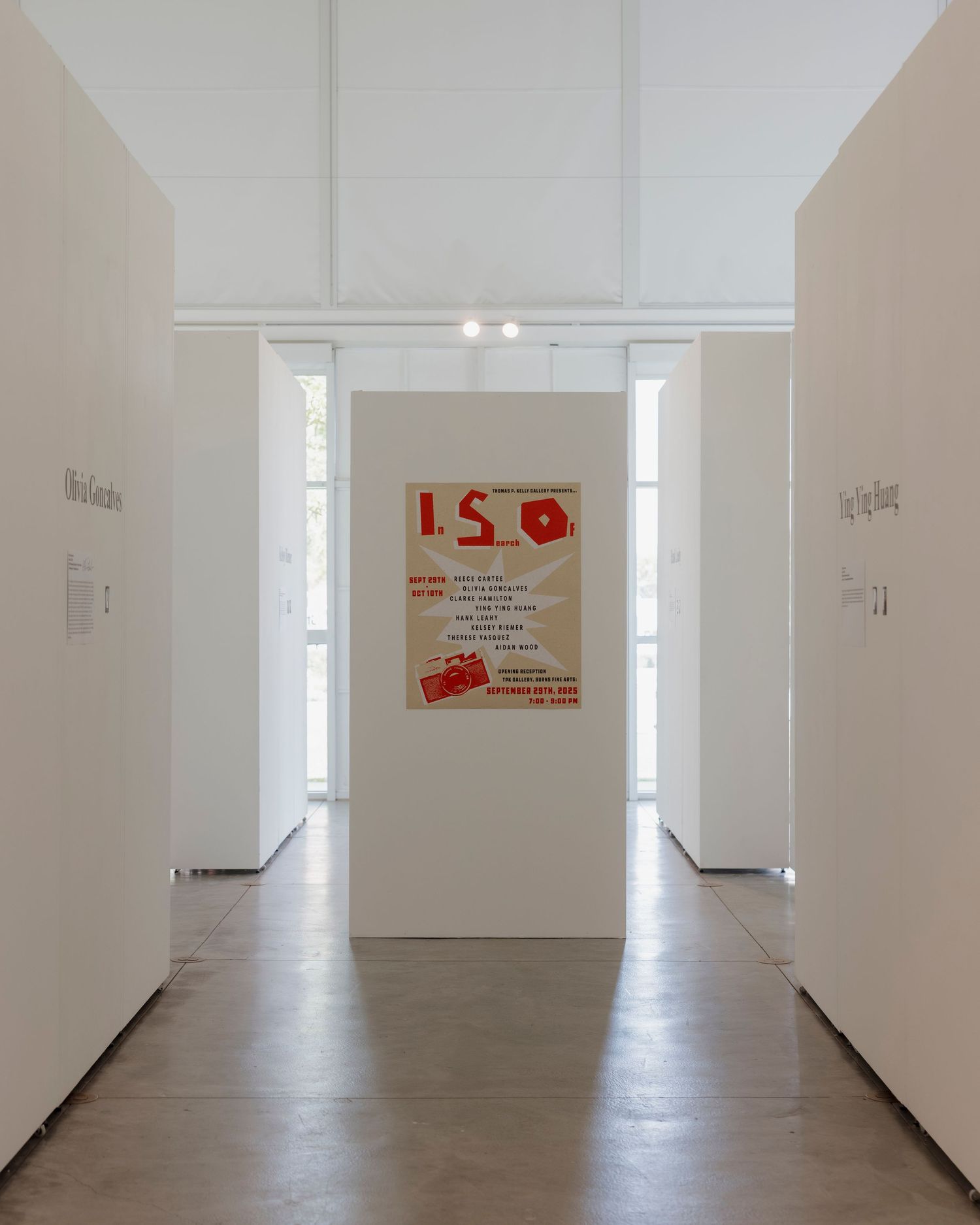 Long white gallery corridor with natural lighting and scattered artwork displays.