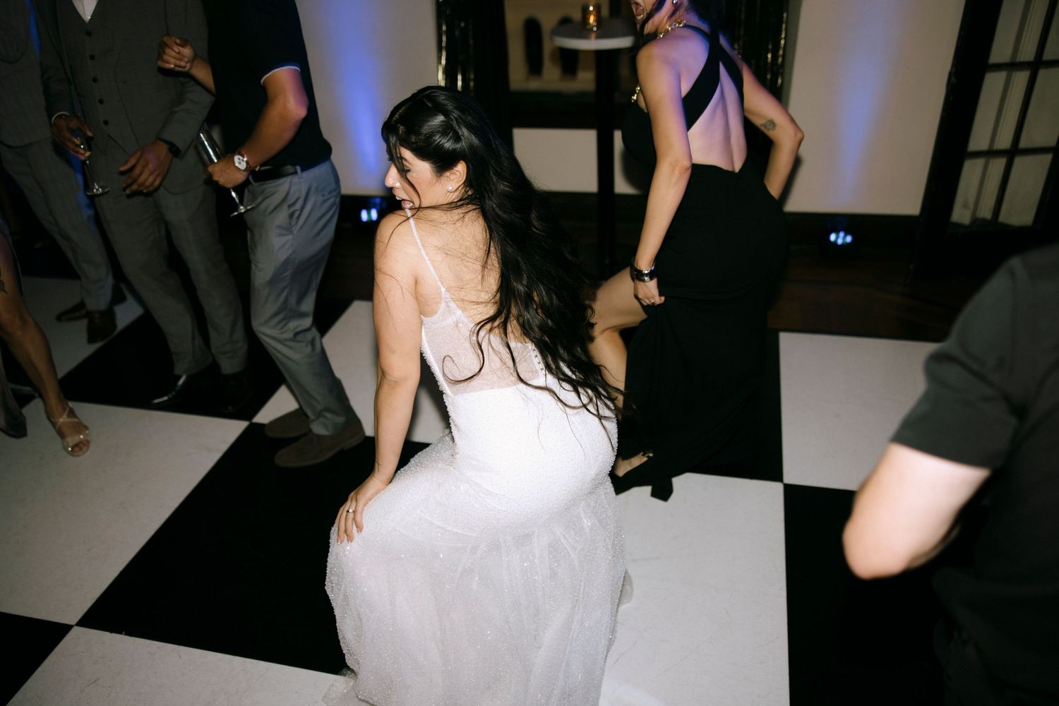 Bride in a white wedding dress dancing on a black and white checkered floor.