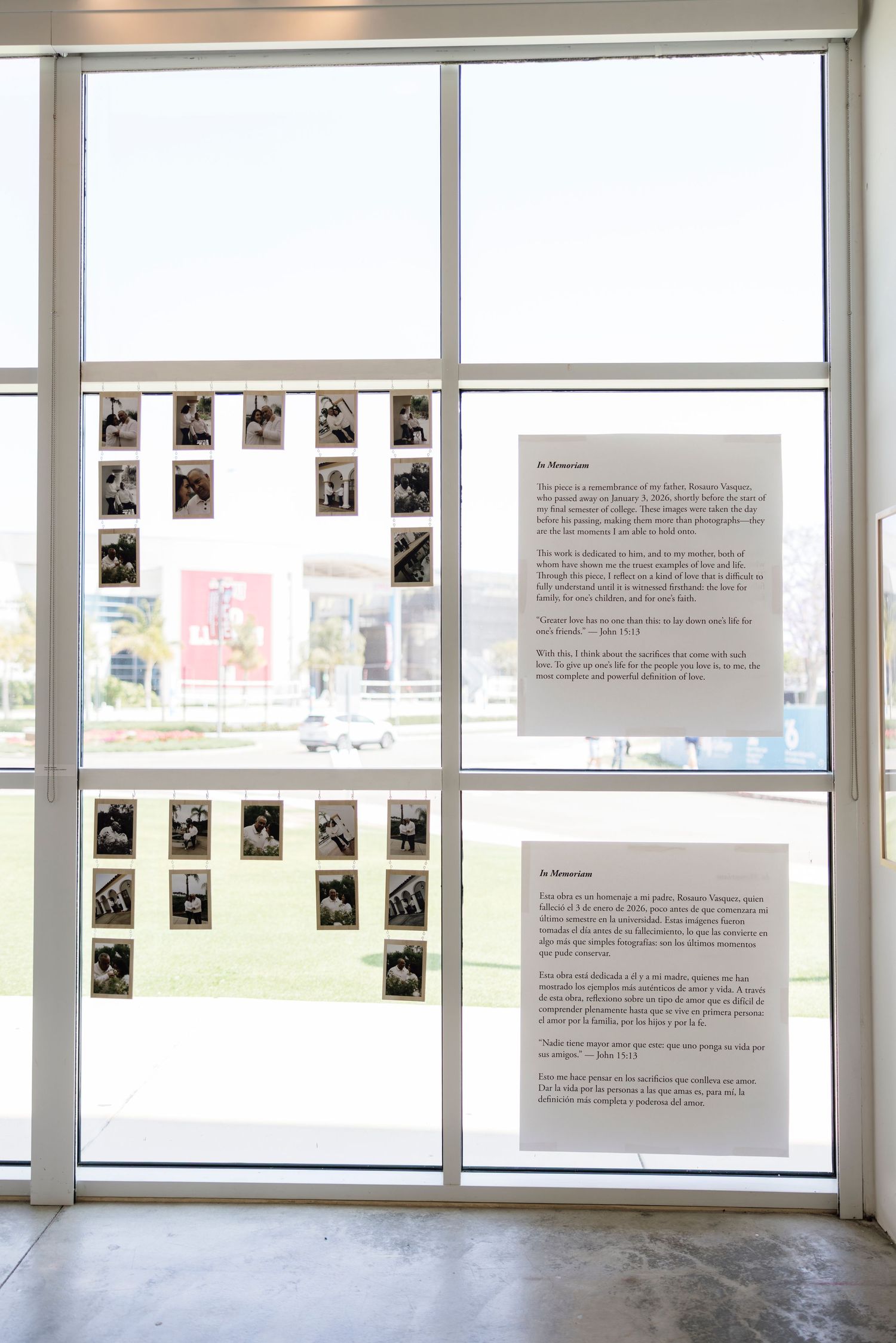 Gallery window display featuring black and white photos and bilingual text panels mounted on large glass doors.