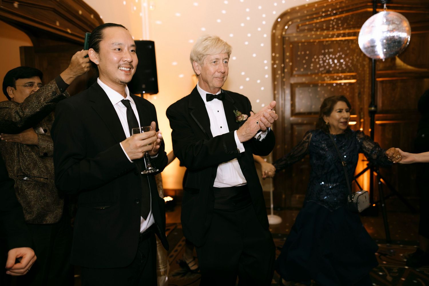 Guests in formal attire dance and celebrate at an elegant indoor venue.