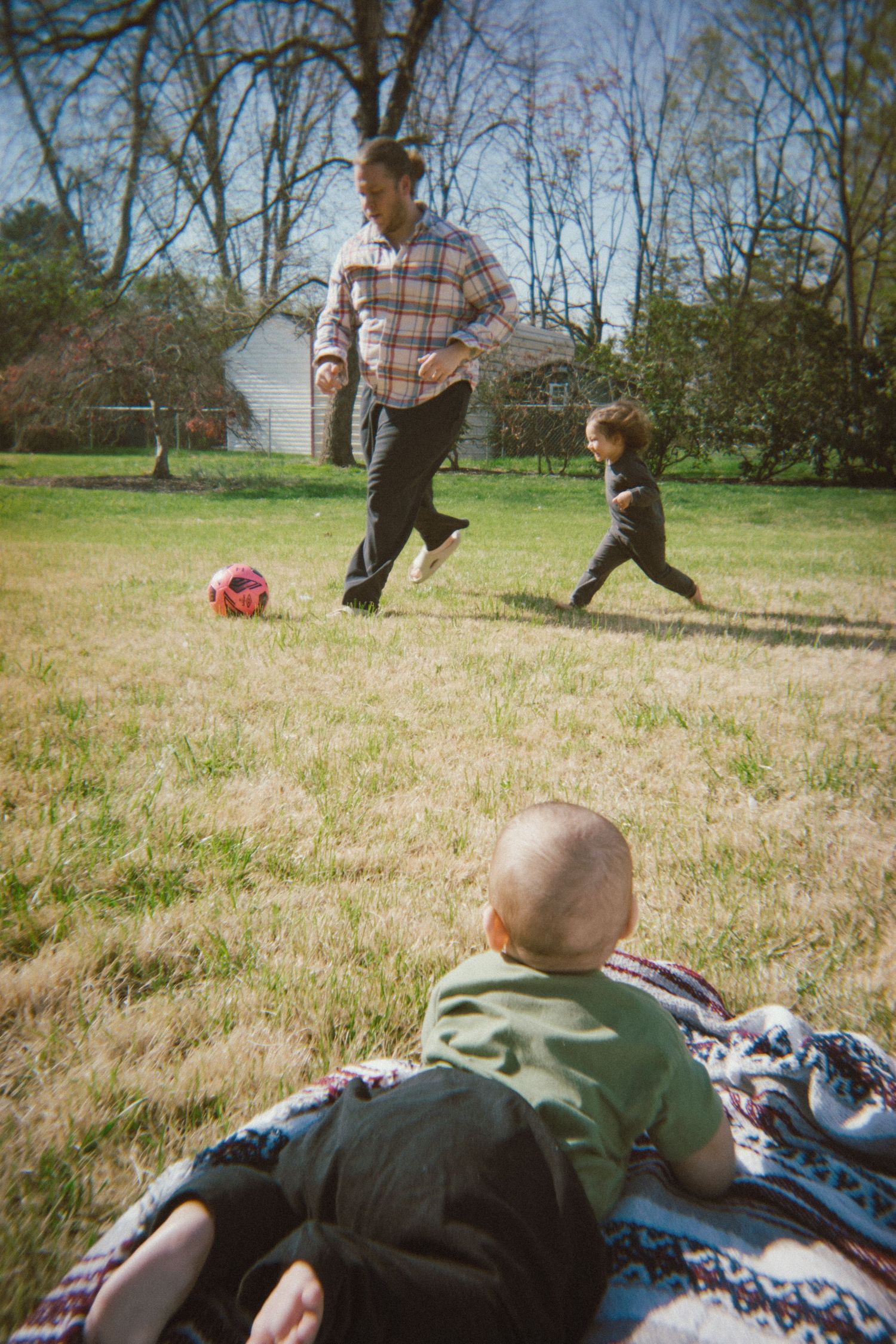 People playing soccer in a backyard while another rests on a blanket. Warrenton, Virginia.