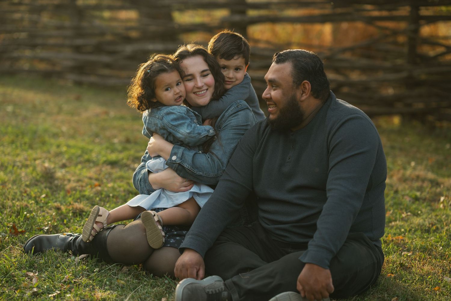 Family relaxing together on grass during golden hour.