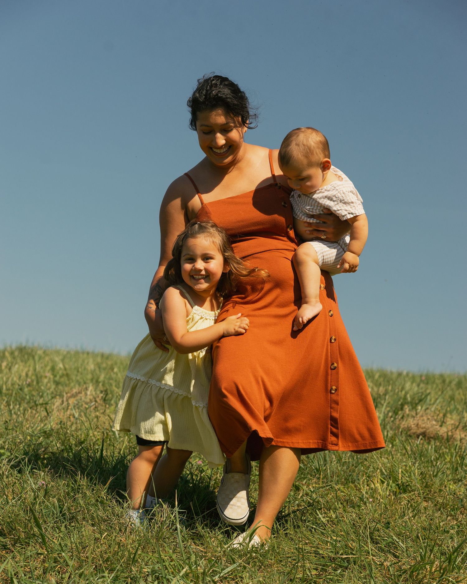 Family group standing together in a grassy field on a sunny summer day.