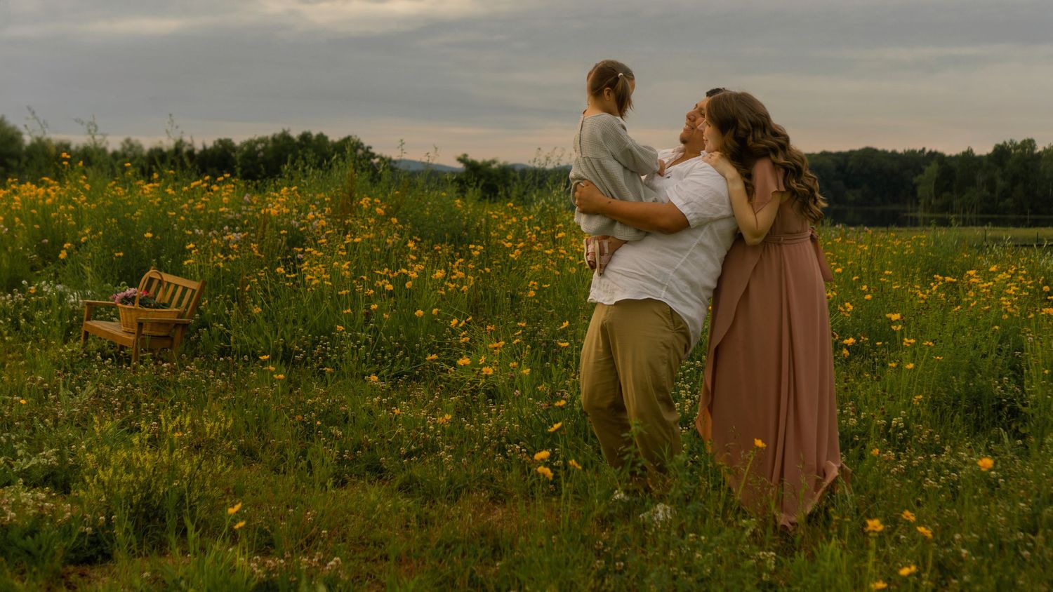 Scenic panorama of a wildflower field at sunset with people in silhouette.