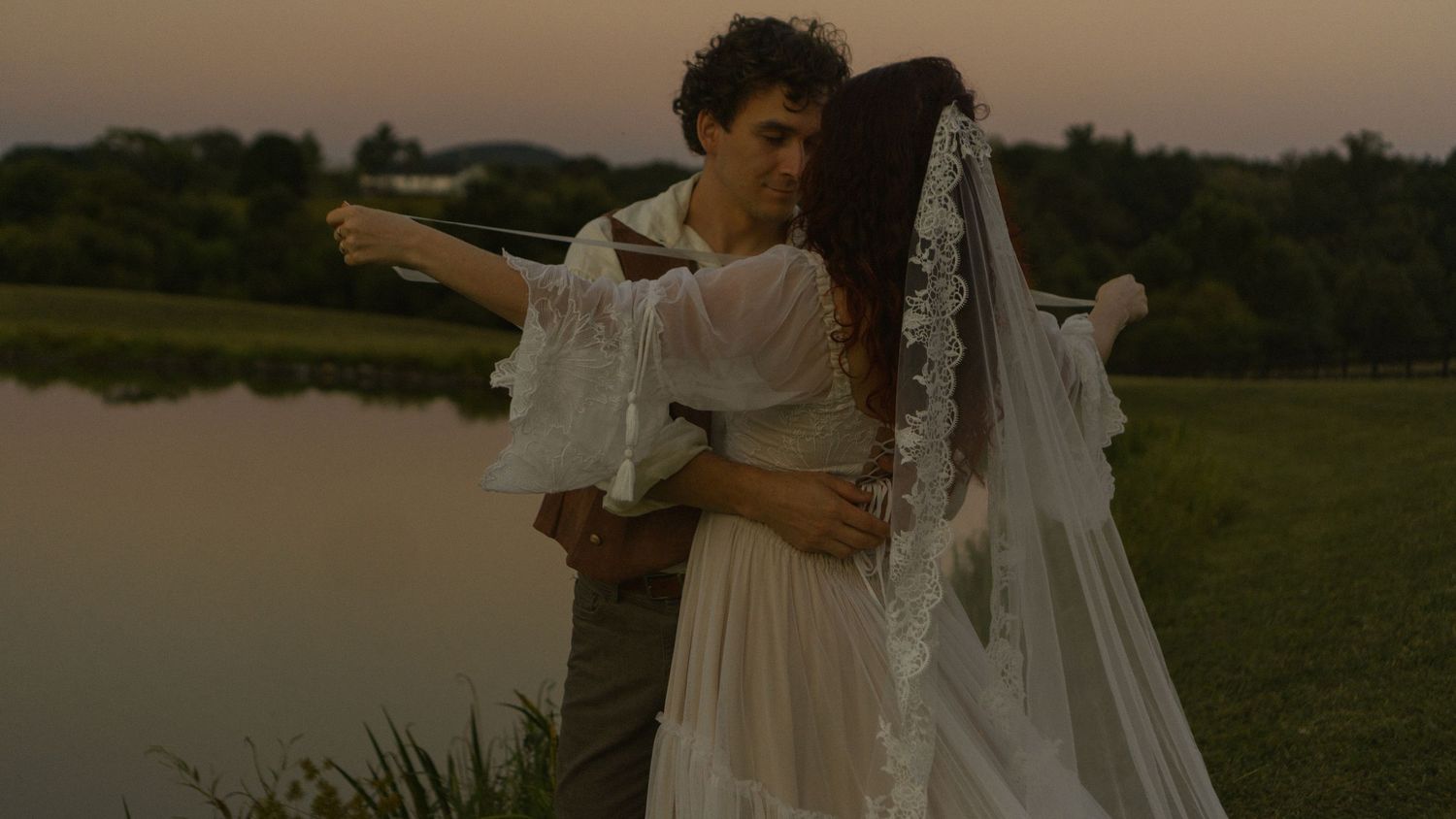 A tender wedding moment captured in warm sunset light with rustic decor and natural outdoor scenery.