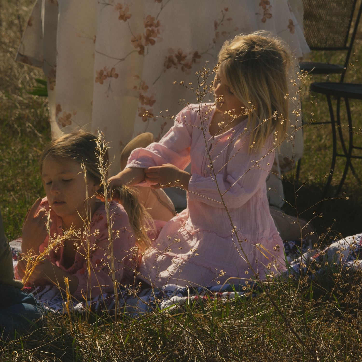 Two people sitting in a sunlit meadow at golden hour creating a dreamy outdoor scene.
