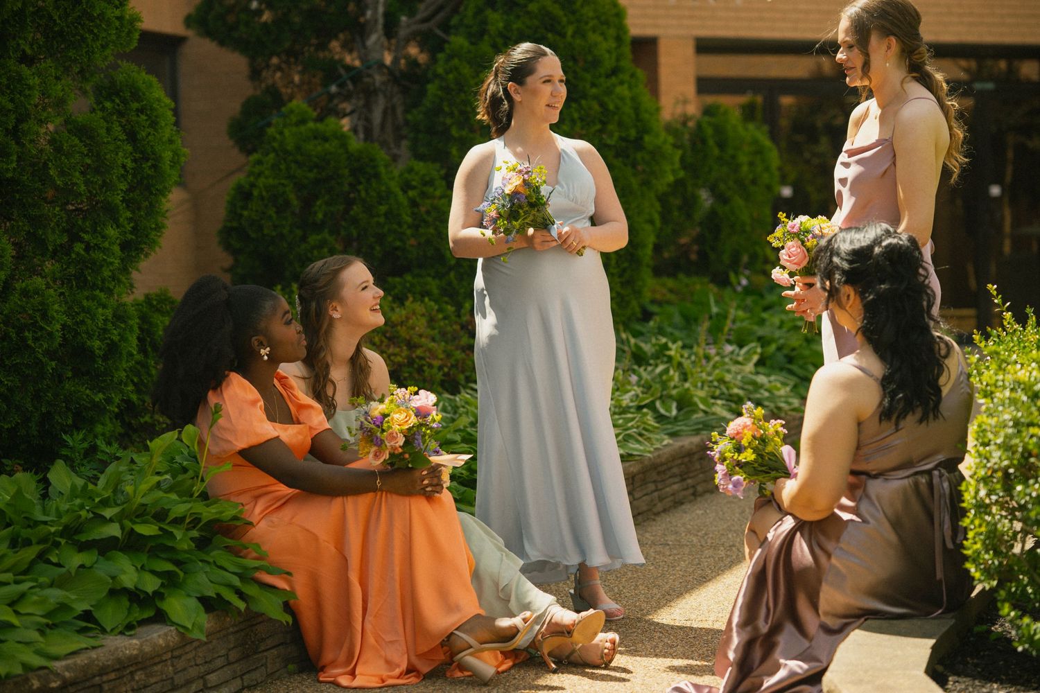 A group of friends enjoying a sunny outdoor gathering with flowers and drinks in a lush garden setting.