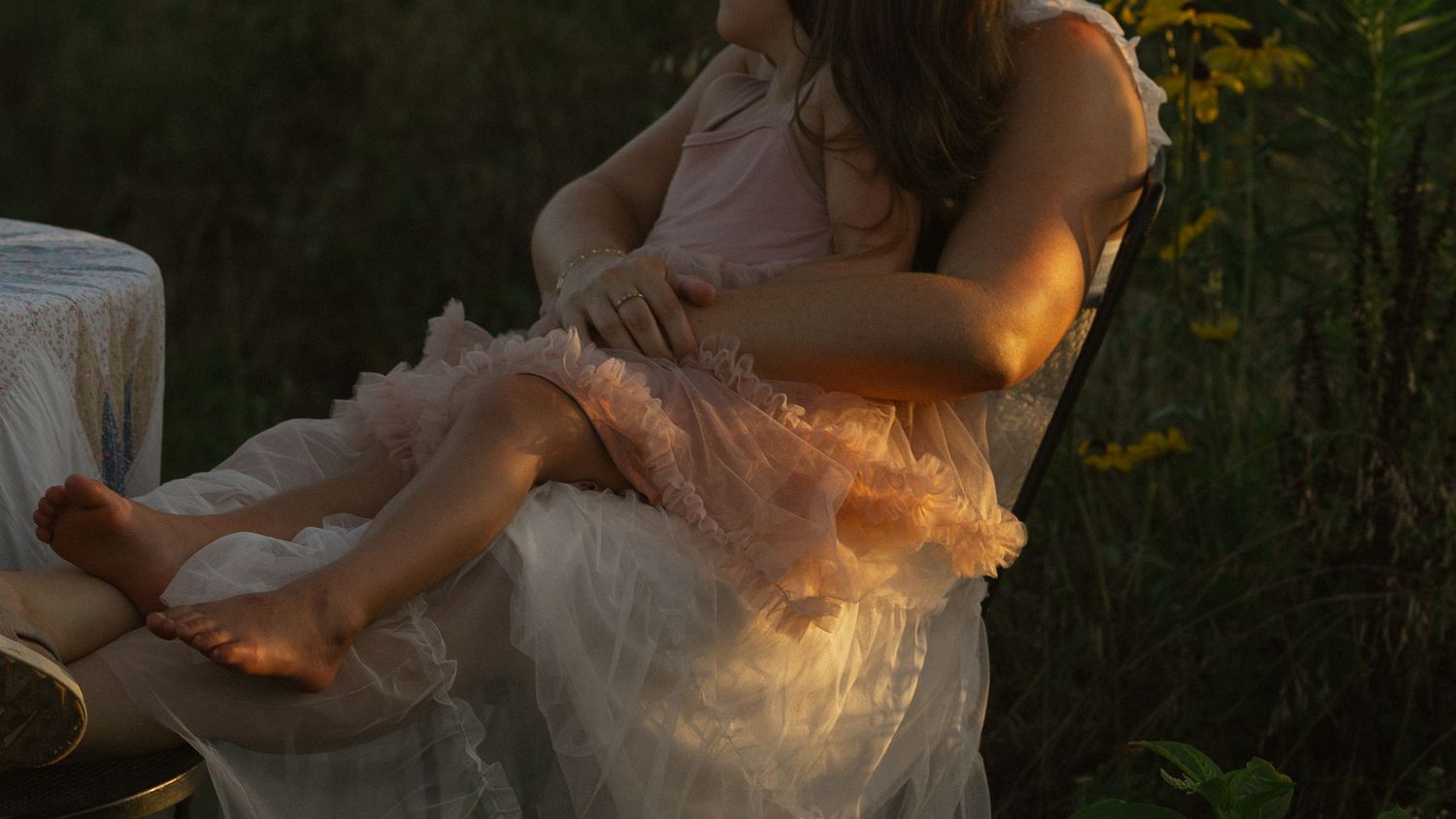 A flowing white dress catches the evening light in a wildflower meadow.