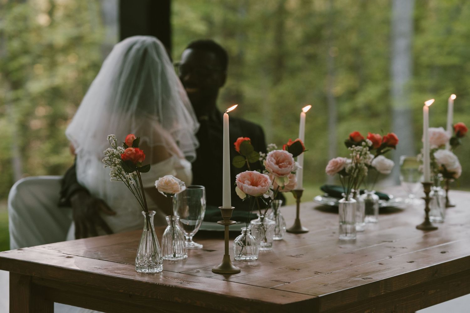 Rustic wedding table setting with candles and floral centerpieces.