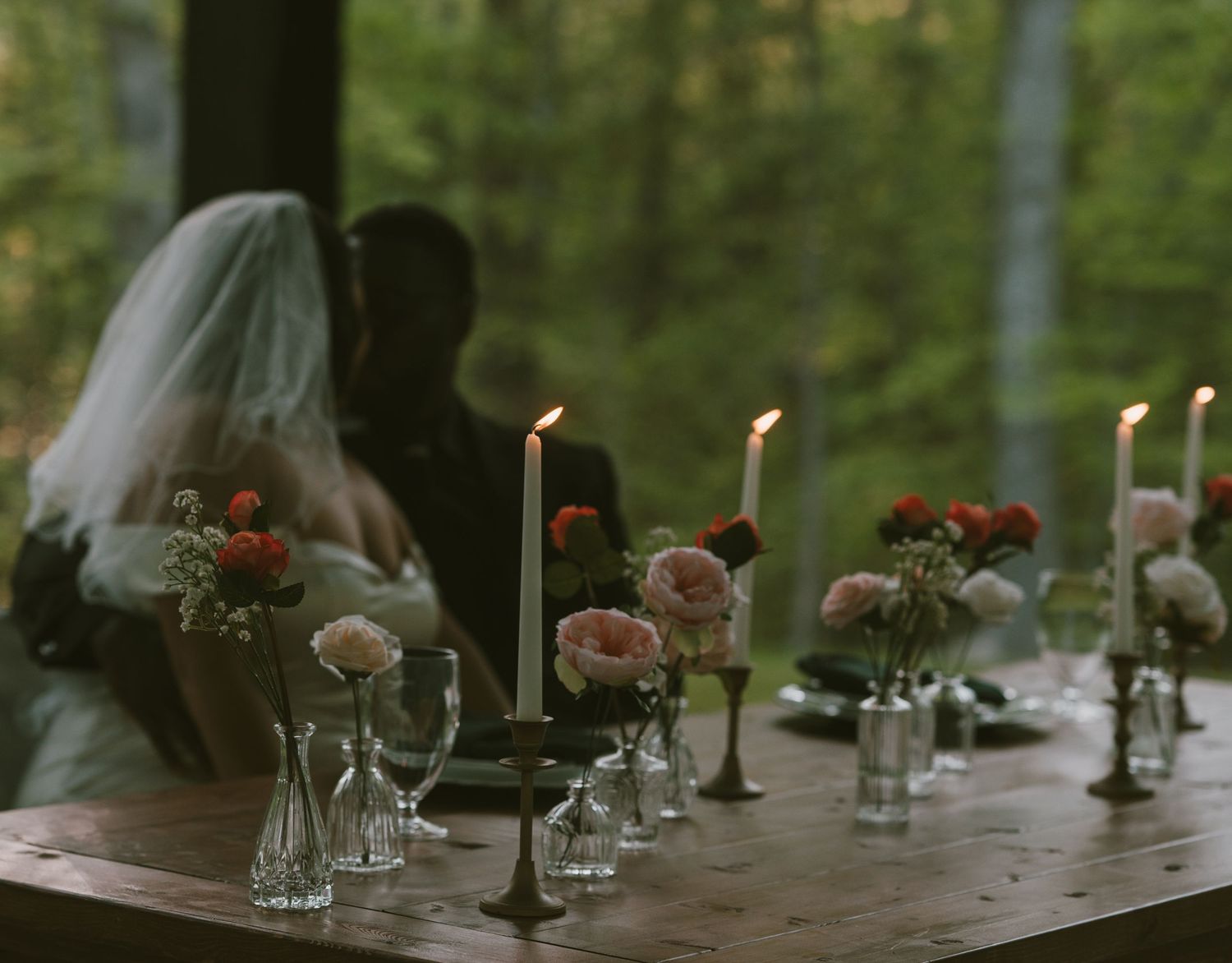 Elegant outdoor table setting with glowing candles and floral centerpieces at dusk.