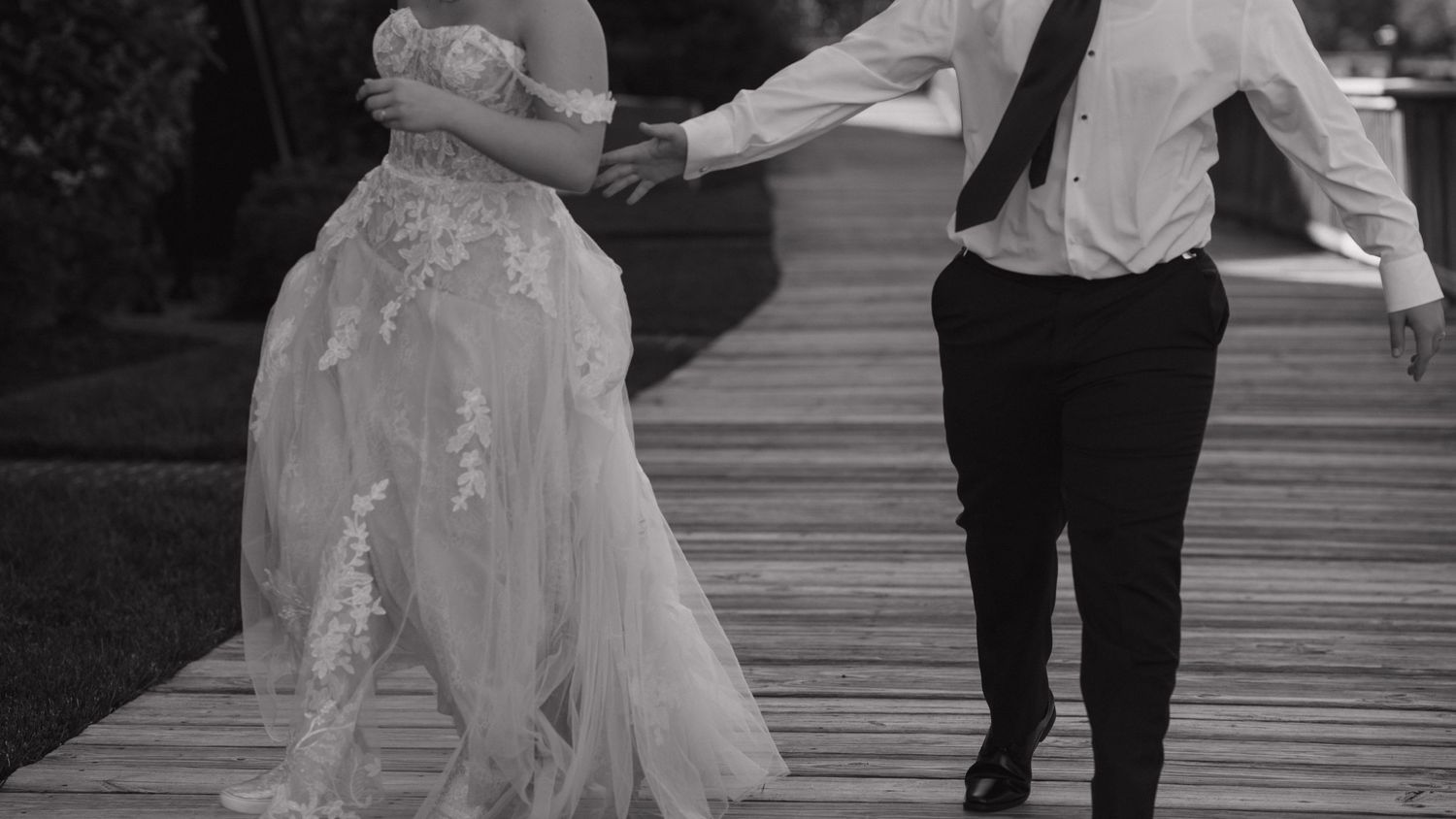 a newly married couple playfully chasing each other down the boardwalk of the marina on the Occoquan River in Virginia