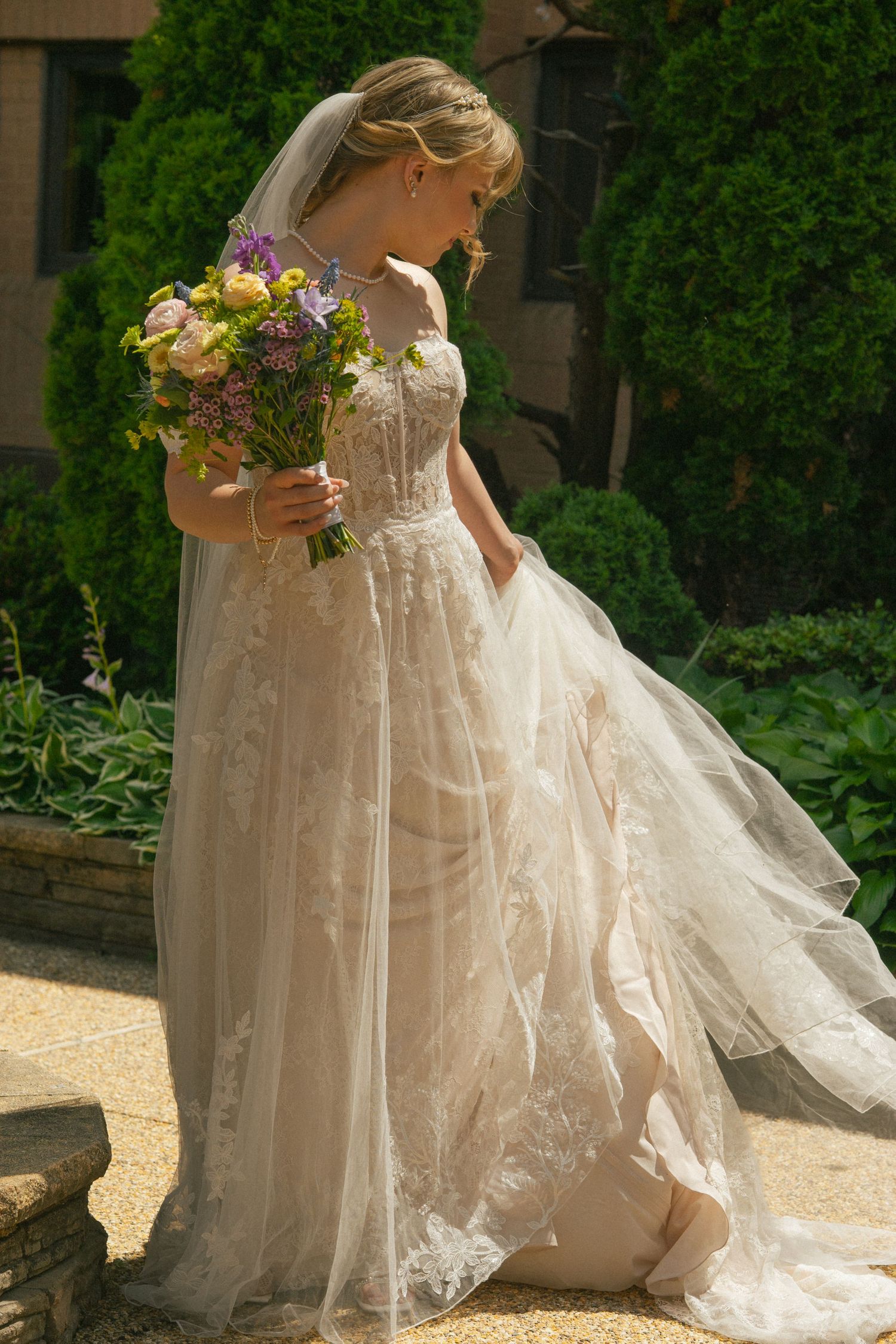 The flowing train of a white wedding dress captured in elegant detail outdoors.