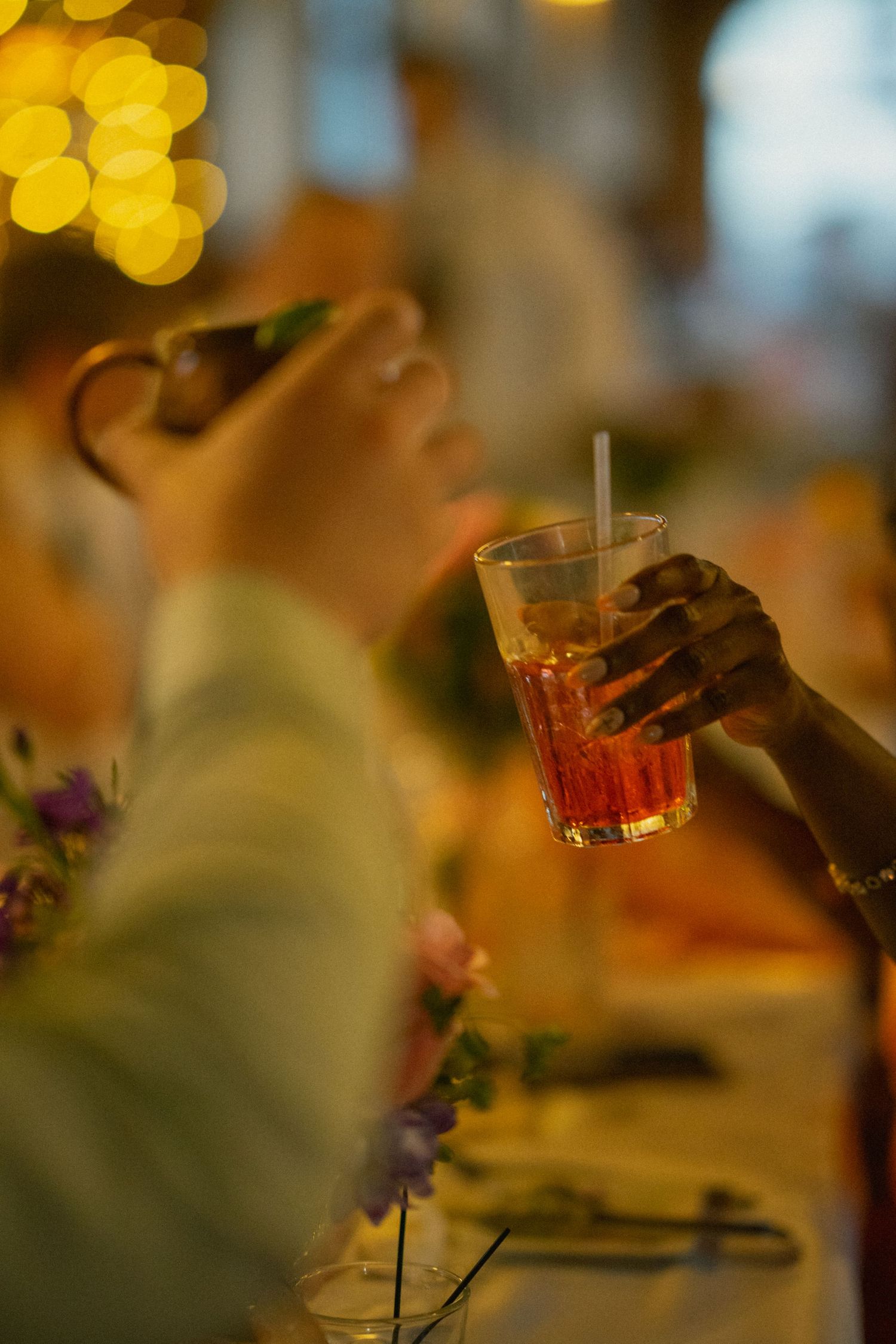 Blurred bokeh lights and drinks create an atmospheric party scene.