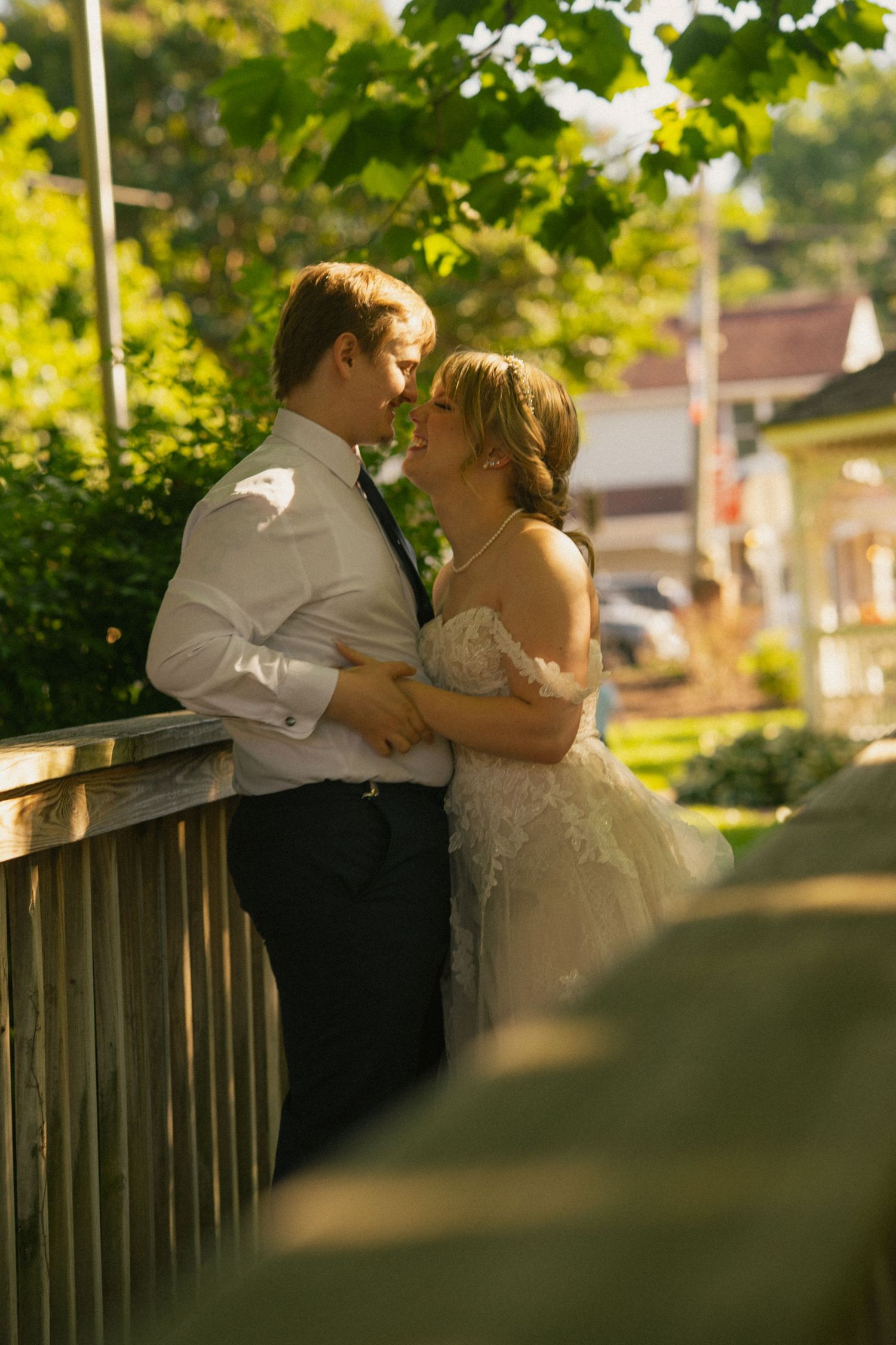 A couple shares an intimate moment on a wooden deck in golden sunlight.